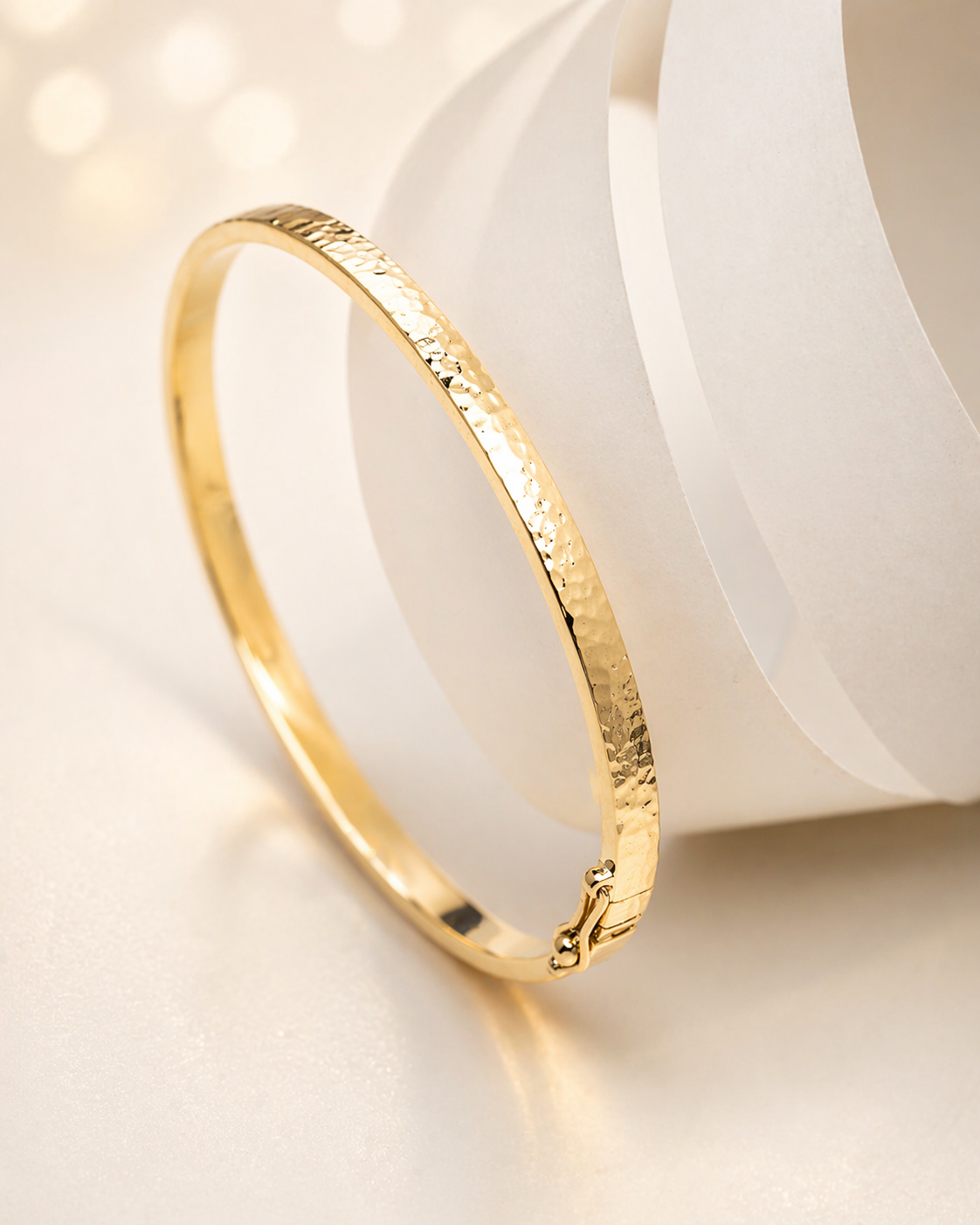 14k Gold hammered bangle bracelet on a soft white background