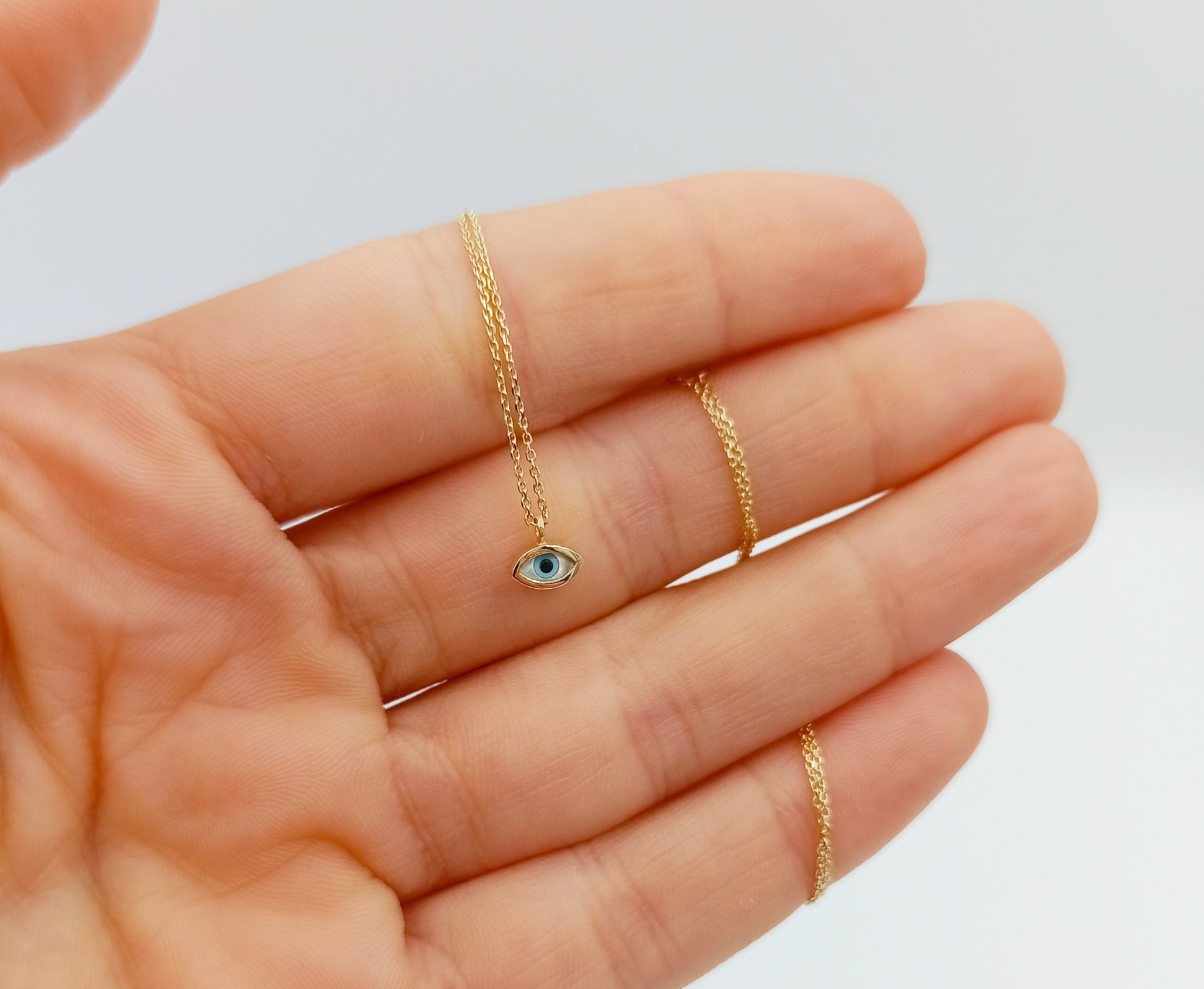 Tiny mother-of-pearl evil eye necklace in 14k gold for women.