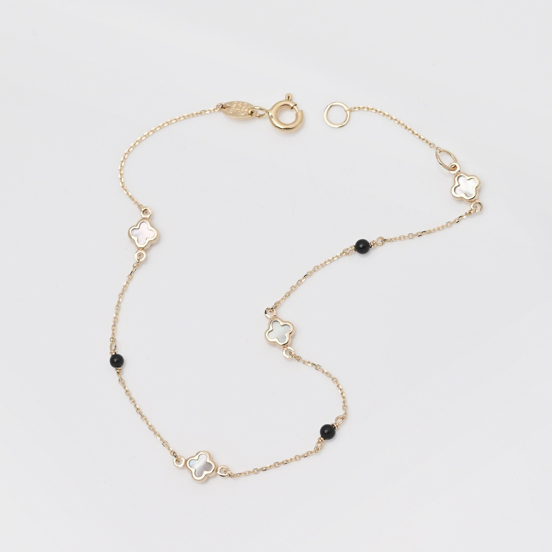 14k gold bracelet with four colver charms and three black onyx beads