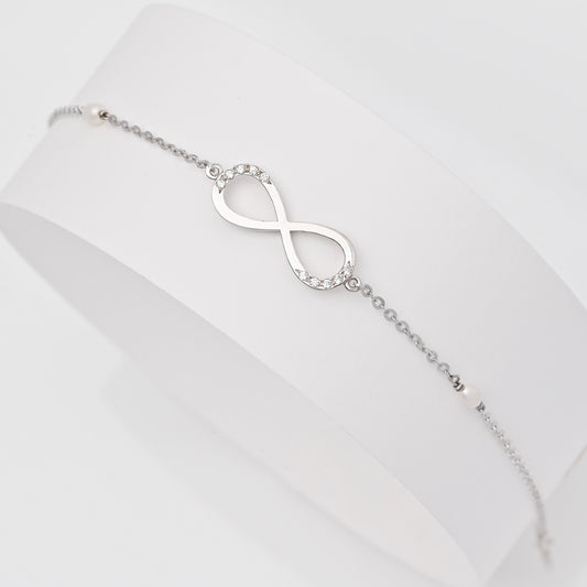 A women's bracelet featuring the infinity symbol in 14k white gold, adorned with cubic zirconia stones and pearls.