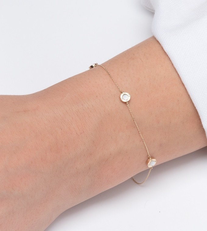 A model wears a Mother of Pearl bracelet featuring four circles and cubic zirconia stones set in 14k gold.