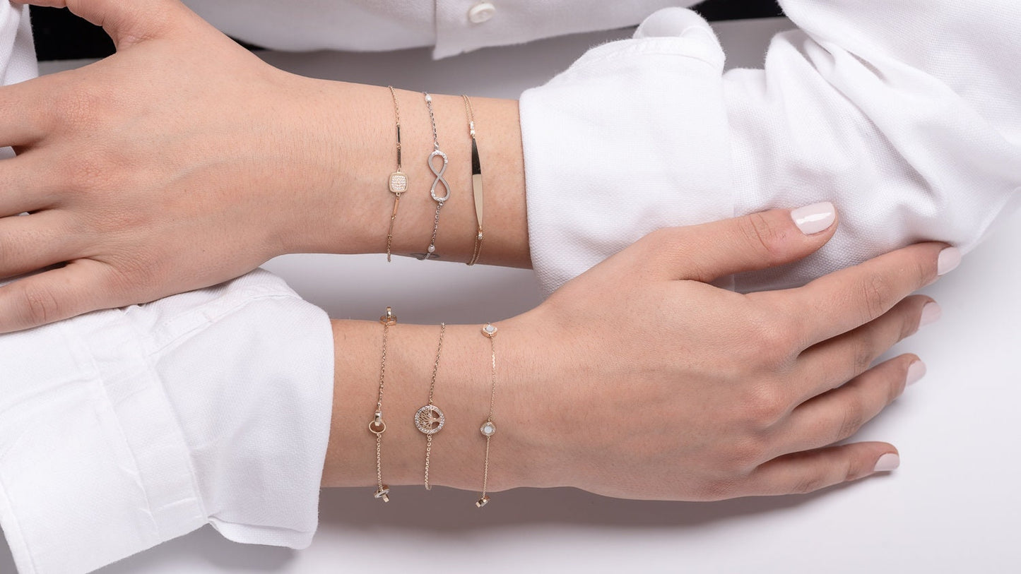 a model wearing dainty charm bracelets on her hands three in each hand by luna oro creations 