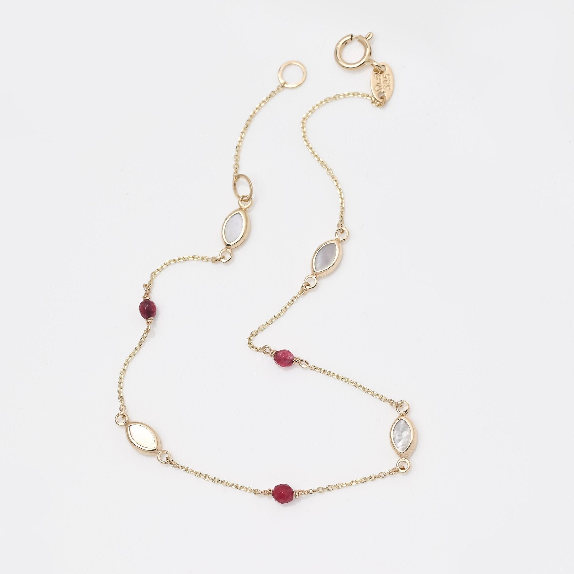 A 14k gold station bracelet adorned with mother of pearl and tourmaline