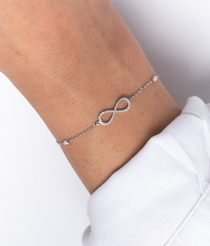 A women's bracelet featuring the infinity symbol in 14k white gold, adorned with cubic zirconia stones and pearls.