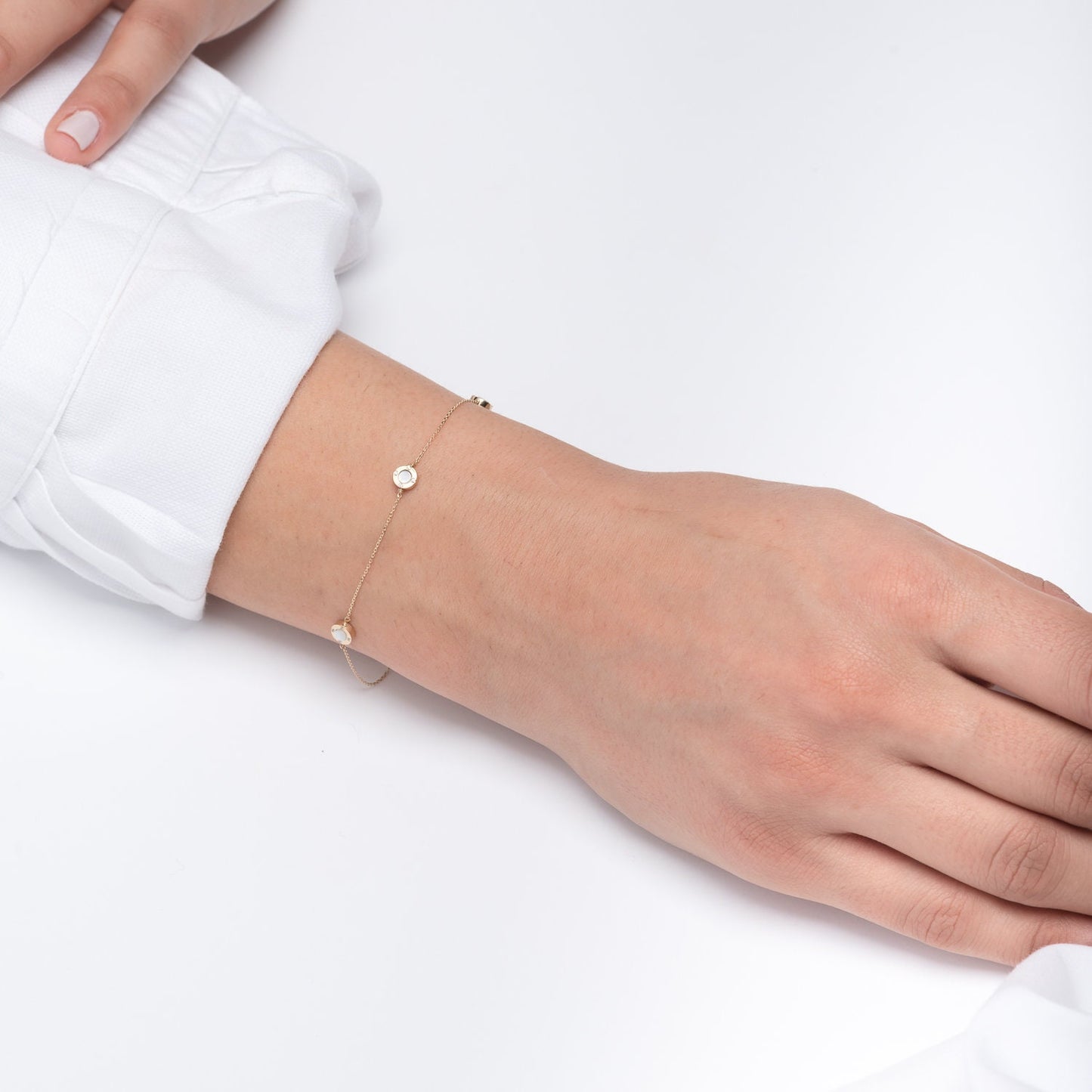 A model wears a Mother of Pearl bracelet featuring four circles and cubic zirconia stones set in 14k gold.