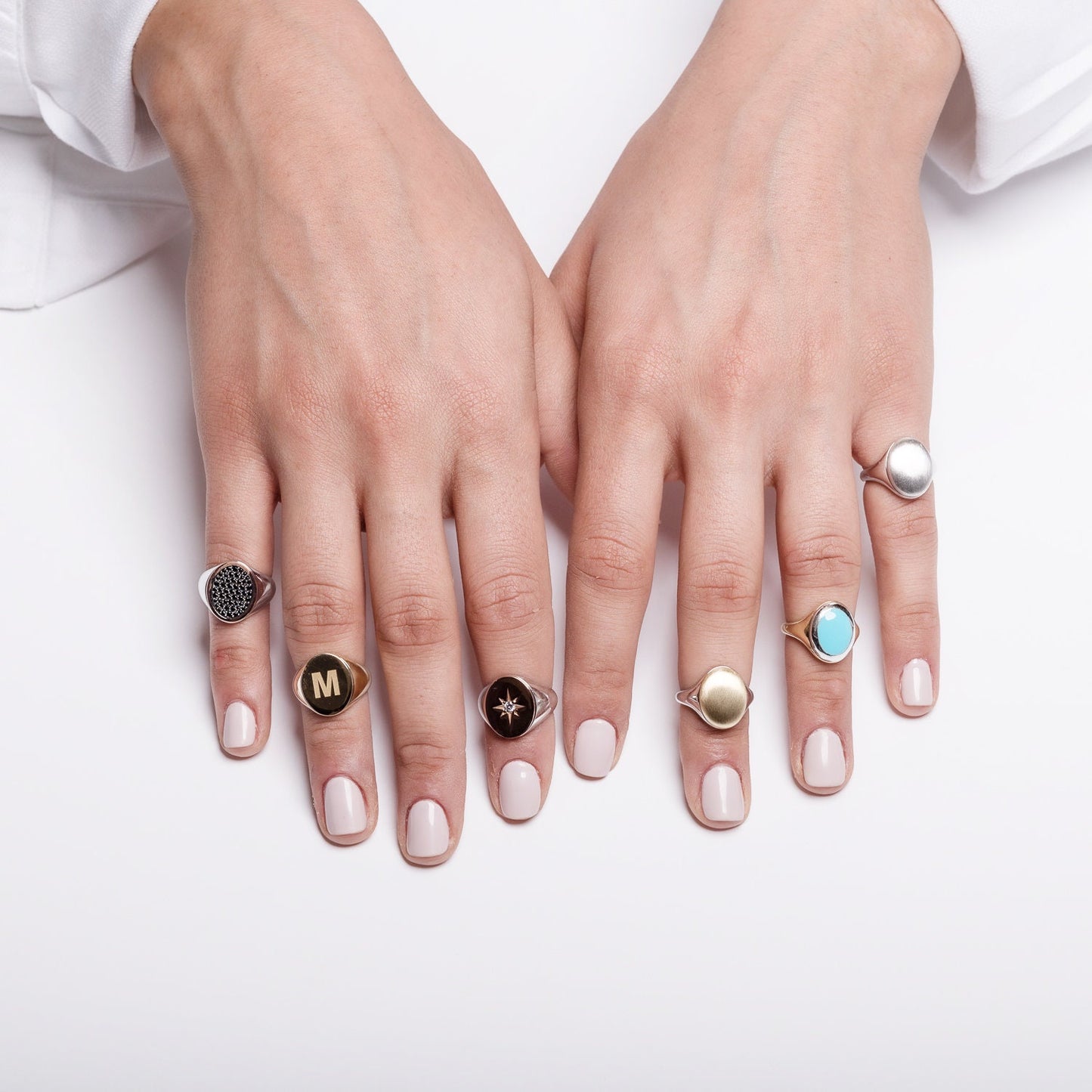 stylish collection of signet rings, featuring various designs worn by a model