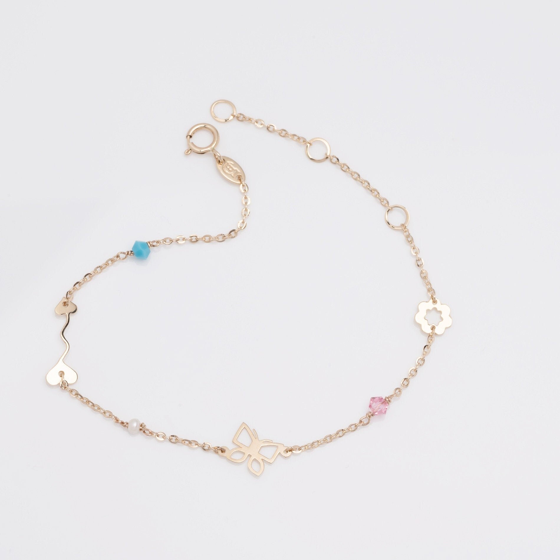 A 14k gold charm bracelet featuring an arrow, a flower, a butterfly, and three colorful gemstones.