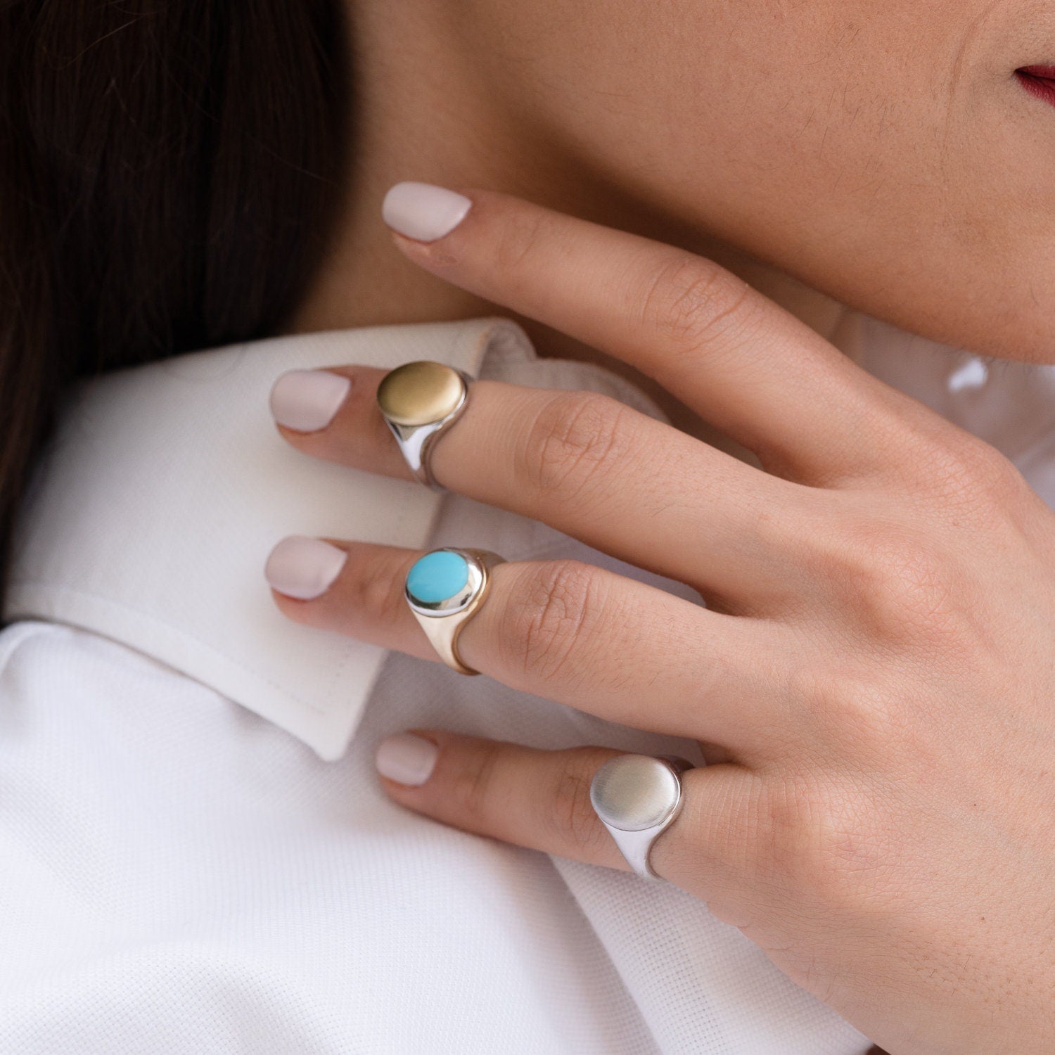 The image shows a close-up of a person's hand wearing three signet rings. The rings are on the index, middle, and ring fingers of the left hand