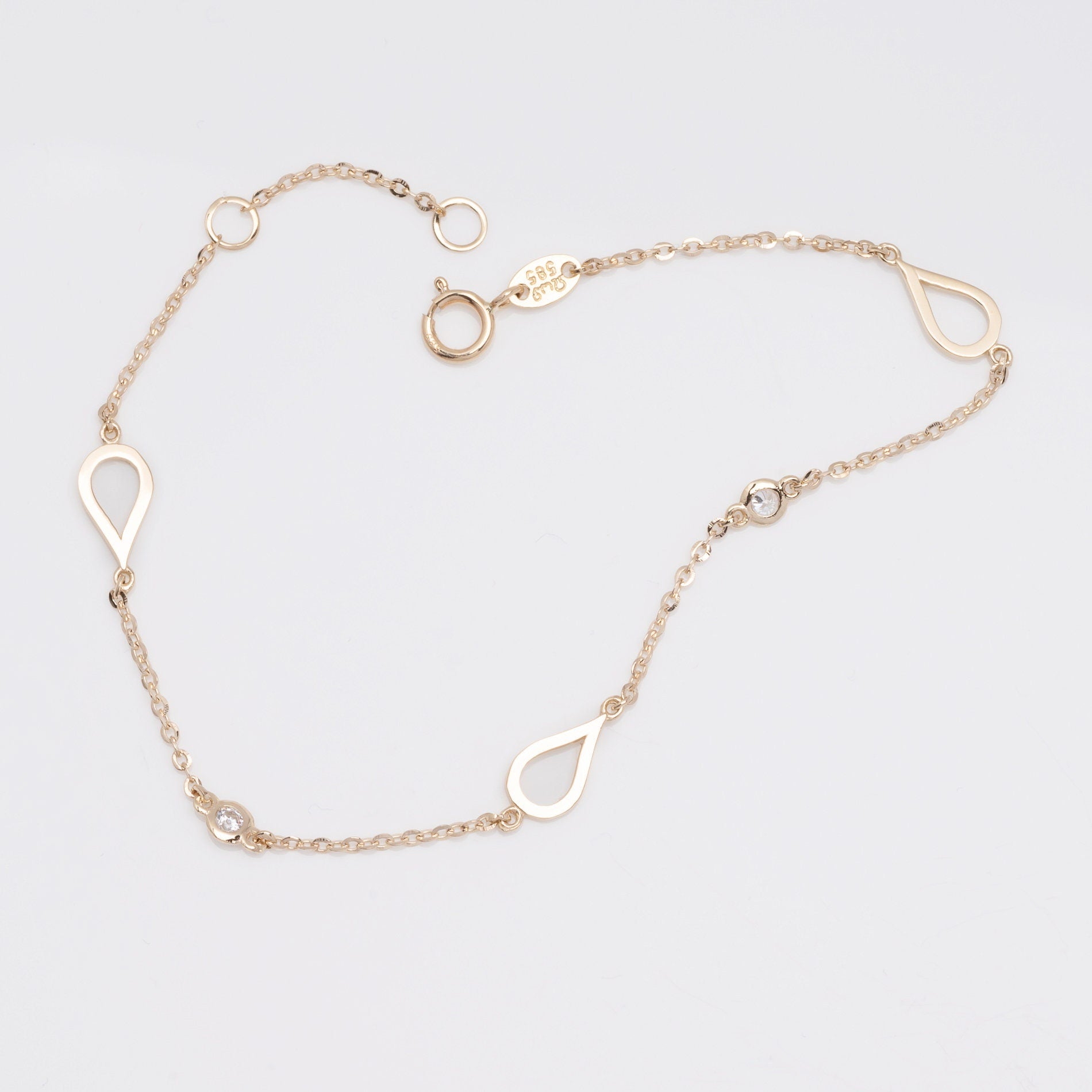 A 14k solid gold bracelet featuring droplets and cubic zirconia stones set in 14k gold.