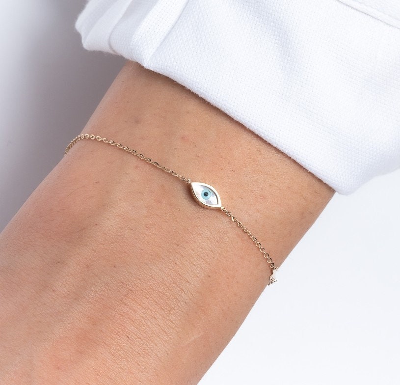 oval evil eye bracelet with cubic zirconia stones and small cross worn by a model 