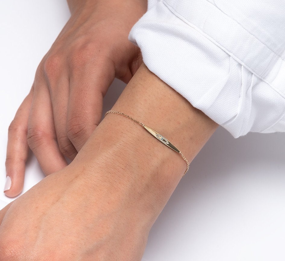 evil eye ID bracelet in 14k yellow gold worn by a model 