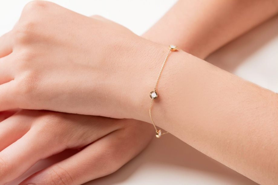 A model wears a Mother of Pearl bracelet featuring four circles and cubic zirconia stones set in 14k gold.