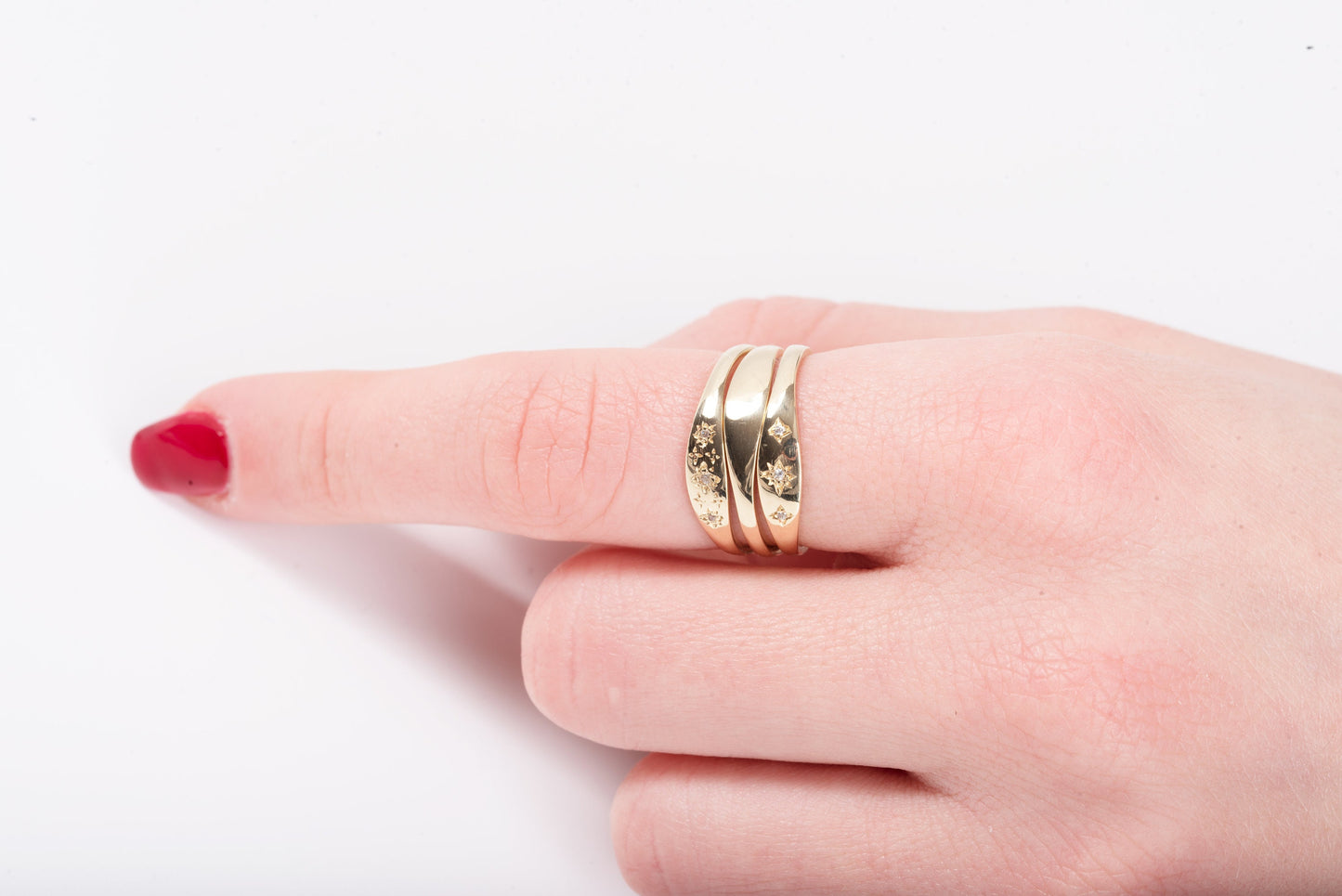 This image features hands adorned with delicate gold rings, showcasing a variety of styles including gemstone accents, twisted bands, and minimalist design