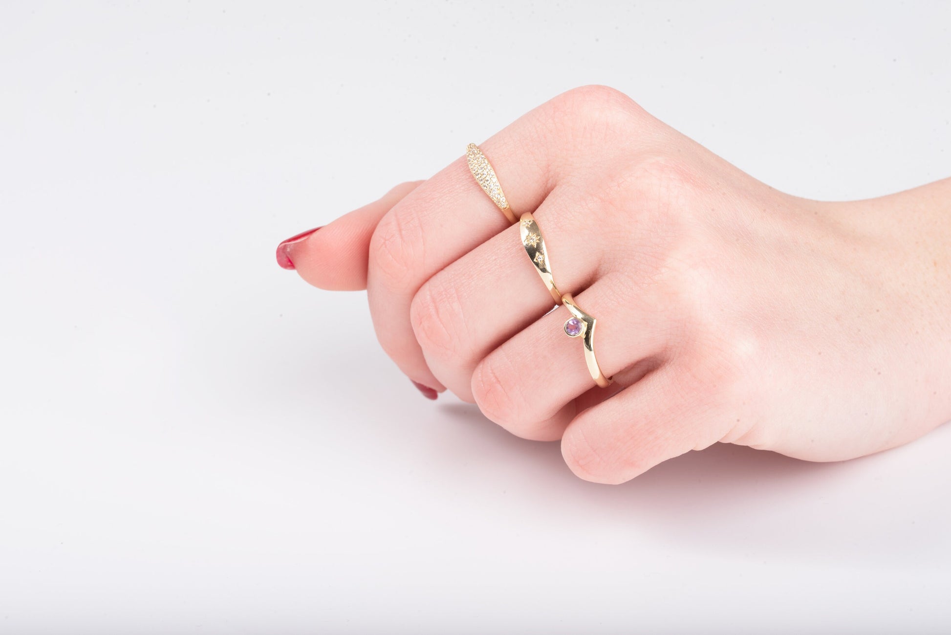 This image features hands adorned with delicate gold rings, showcasing a variety of styles including gemstone accents, twisted bands, and minimalist design