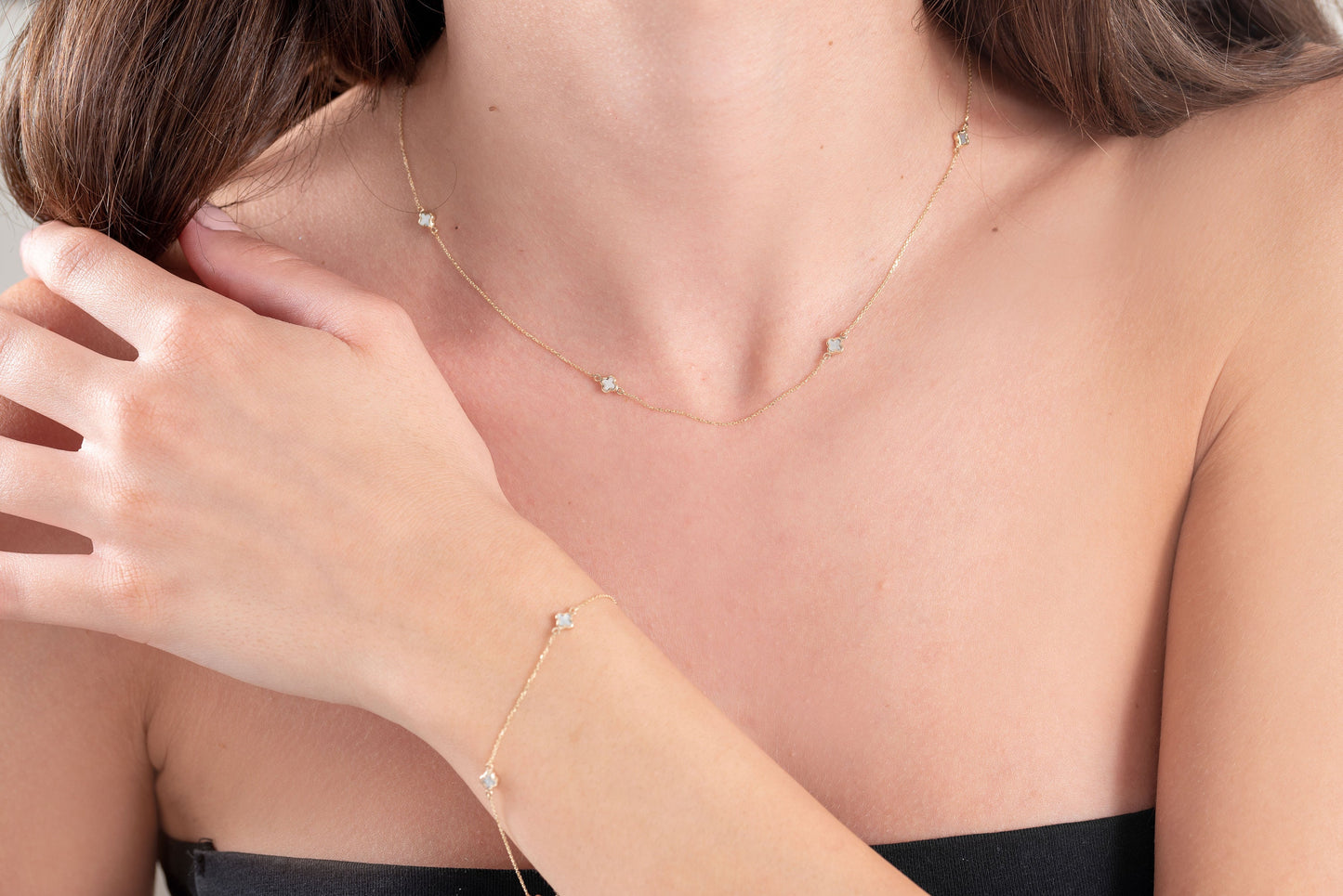 a set of necklace and bracelet with mother of pearl Four Leaf Clover in 14k gold worn by a model