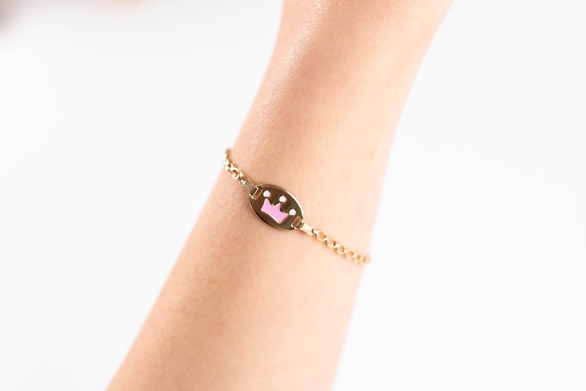 kids bracelet with an enamel crown in 14k gold worn by a model 