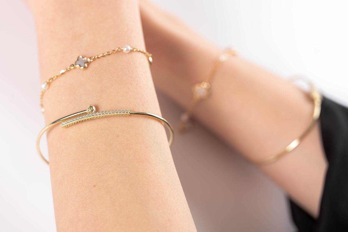 a hand wearing differnet style gold bracelets for women