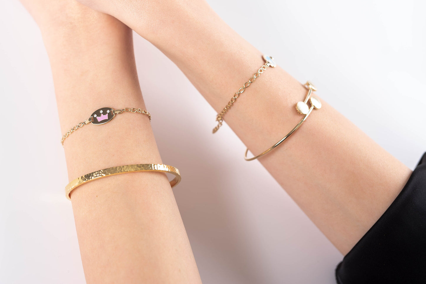 a model wearing 14k gold bracelets two in each hand