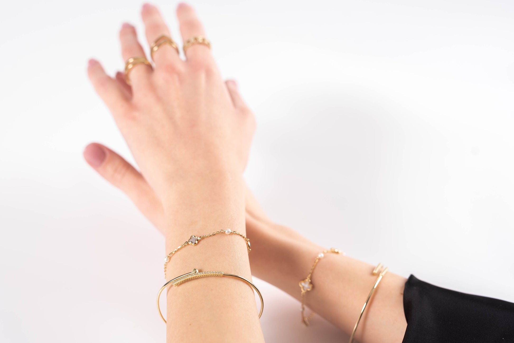 a hand wearing differnet style gold bracelets for women