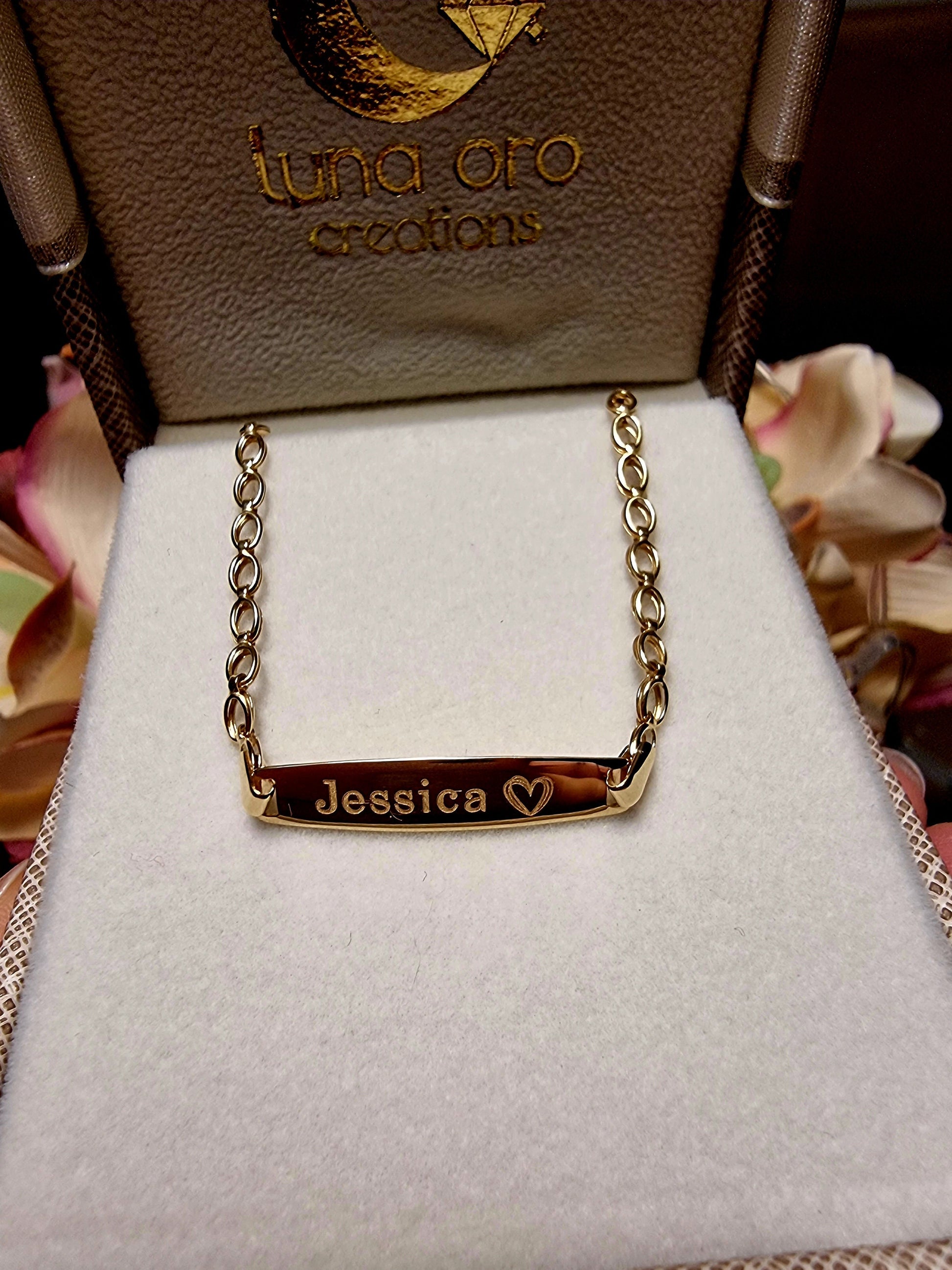 An adult ID bracelet in 14k gold, engraved with the name 'Jessica' and a heart.