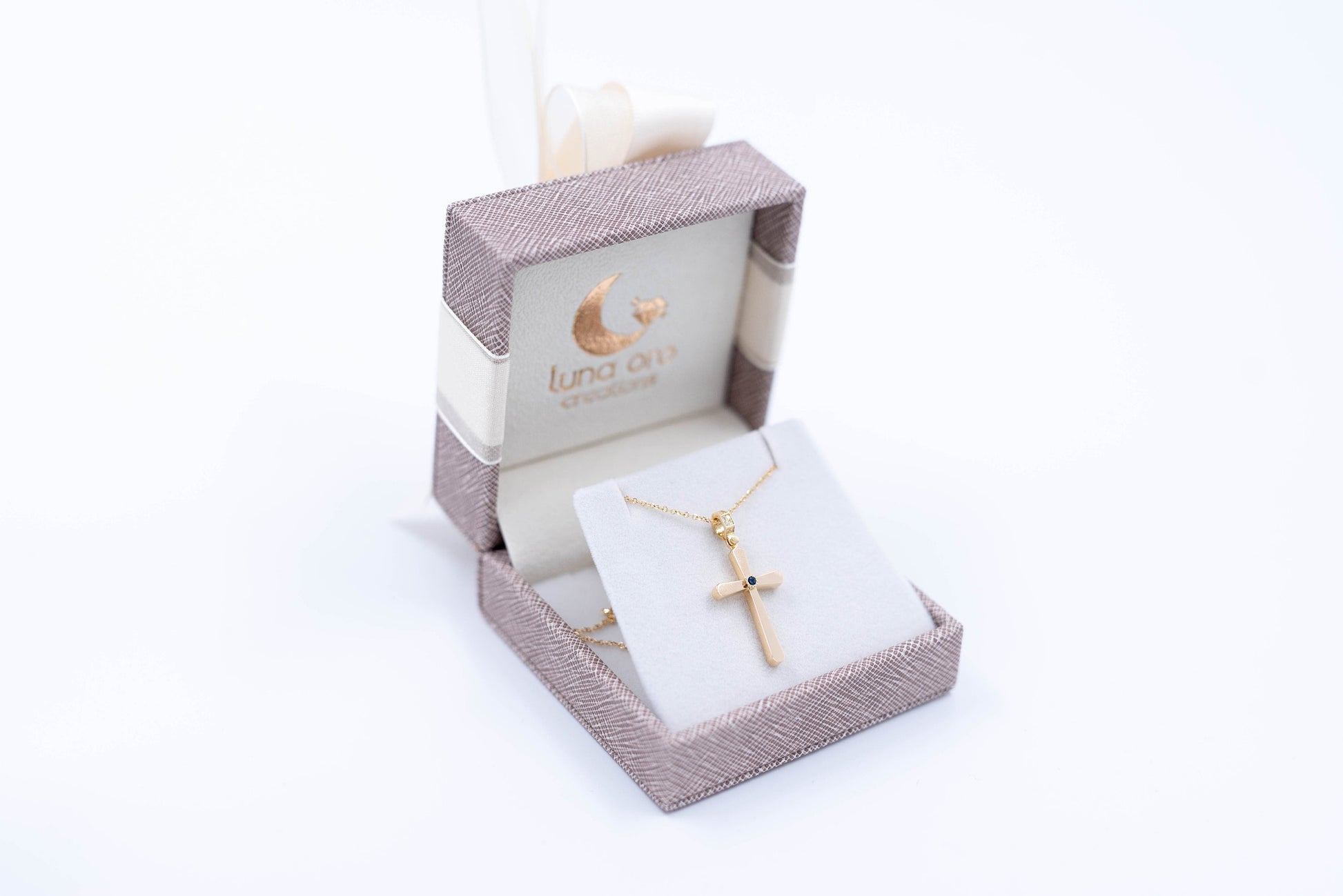 Leather jewelry box featuring a 14k gold cross, crafted by Luna Oro Creations.