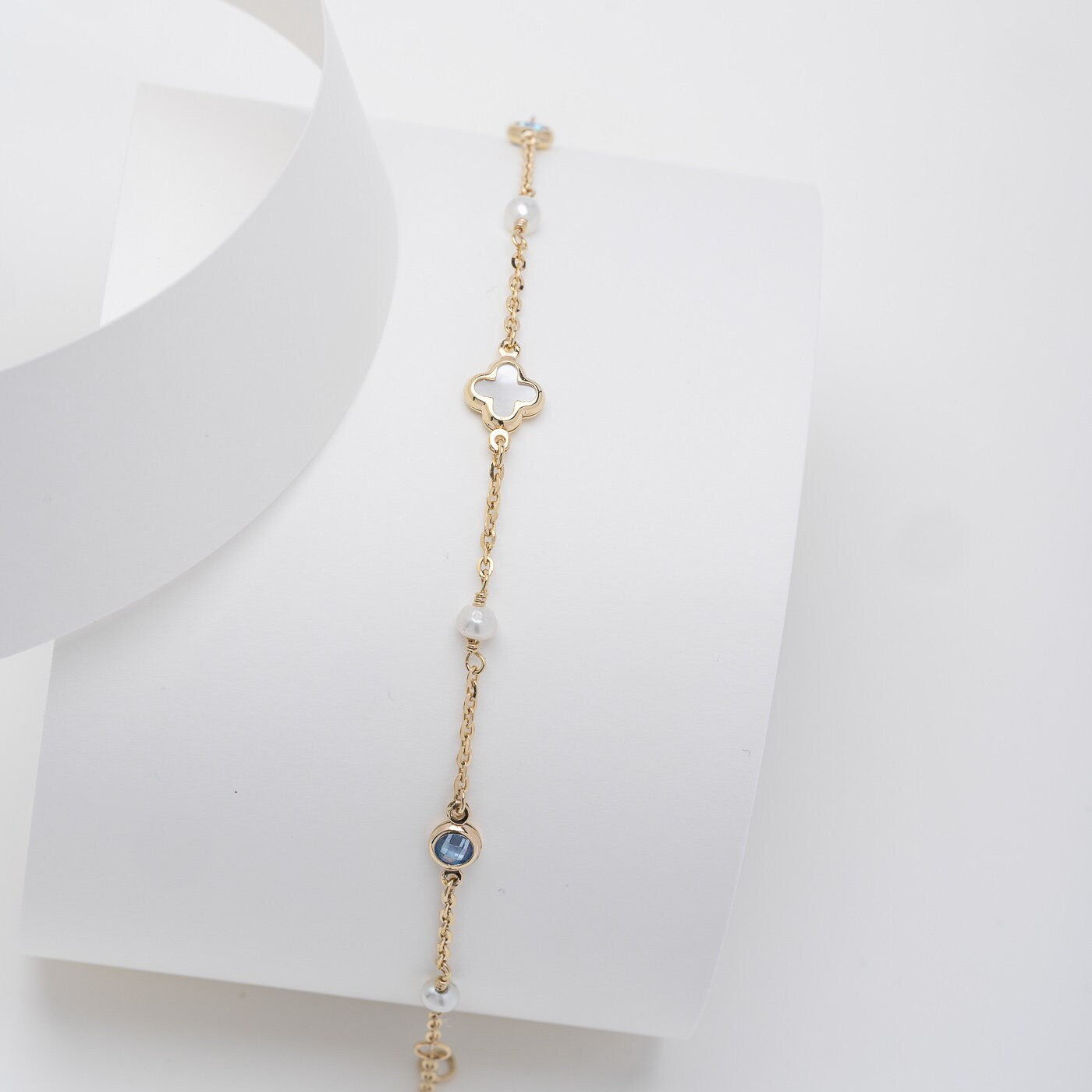 14k gold bracelet with a four leaf clover, four freshwater pearls, two aquamarine stones