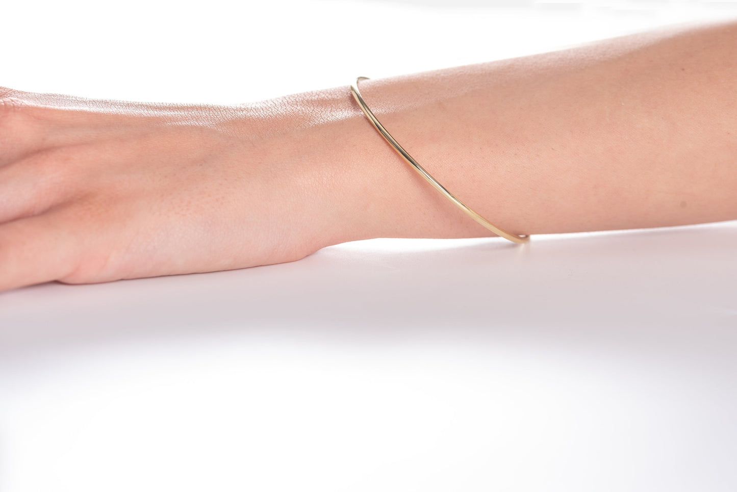 Slip on a 14k Gold Bangle Bracelet for women, showcased by a model.