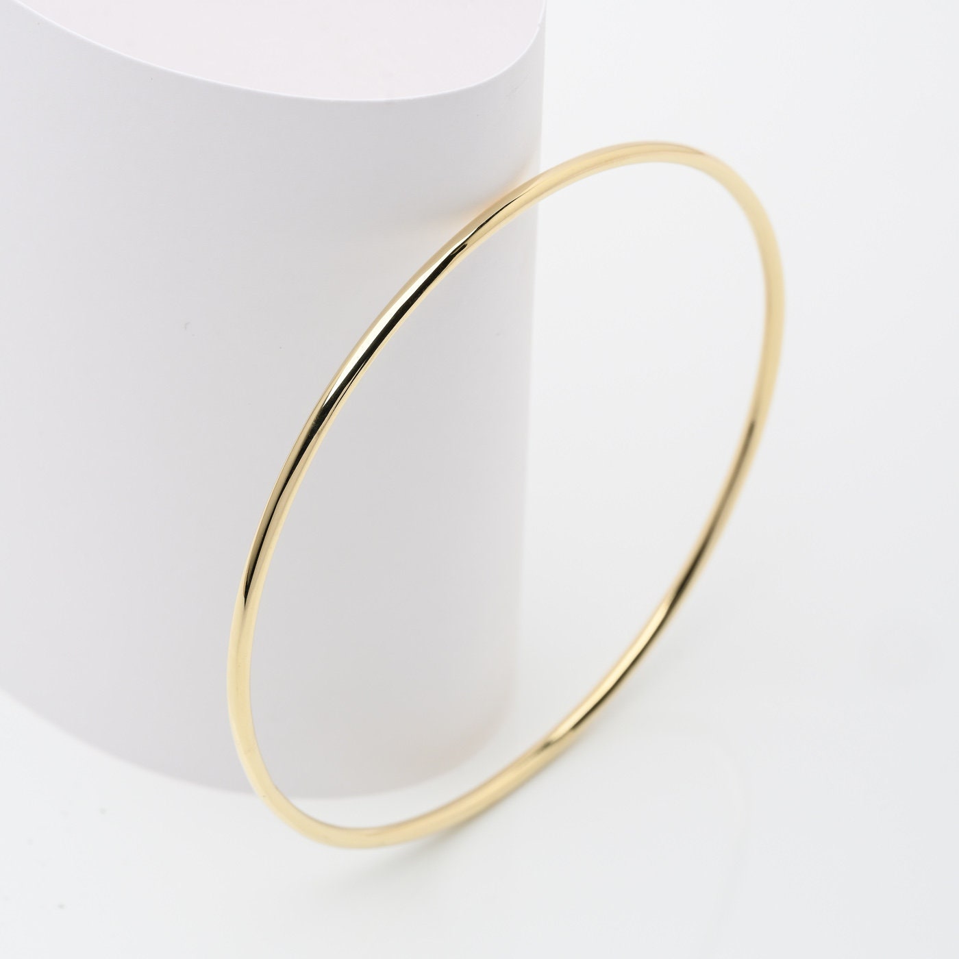 Slip on a 14k Gold Bangle Bracelet for women, showcased by a model.