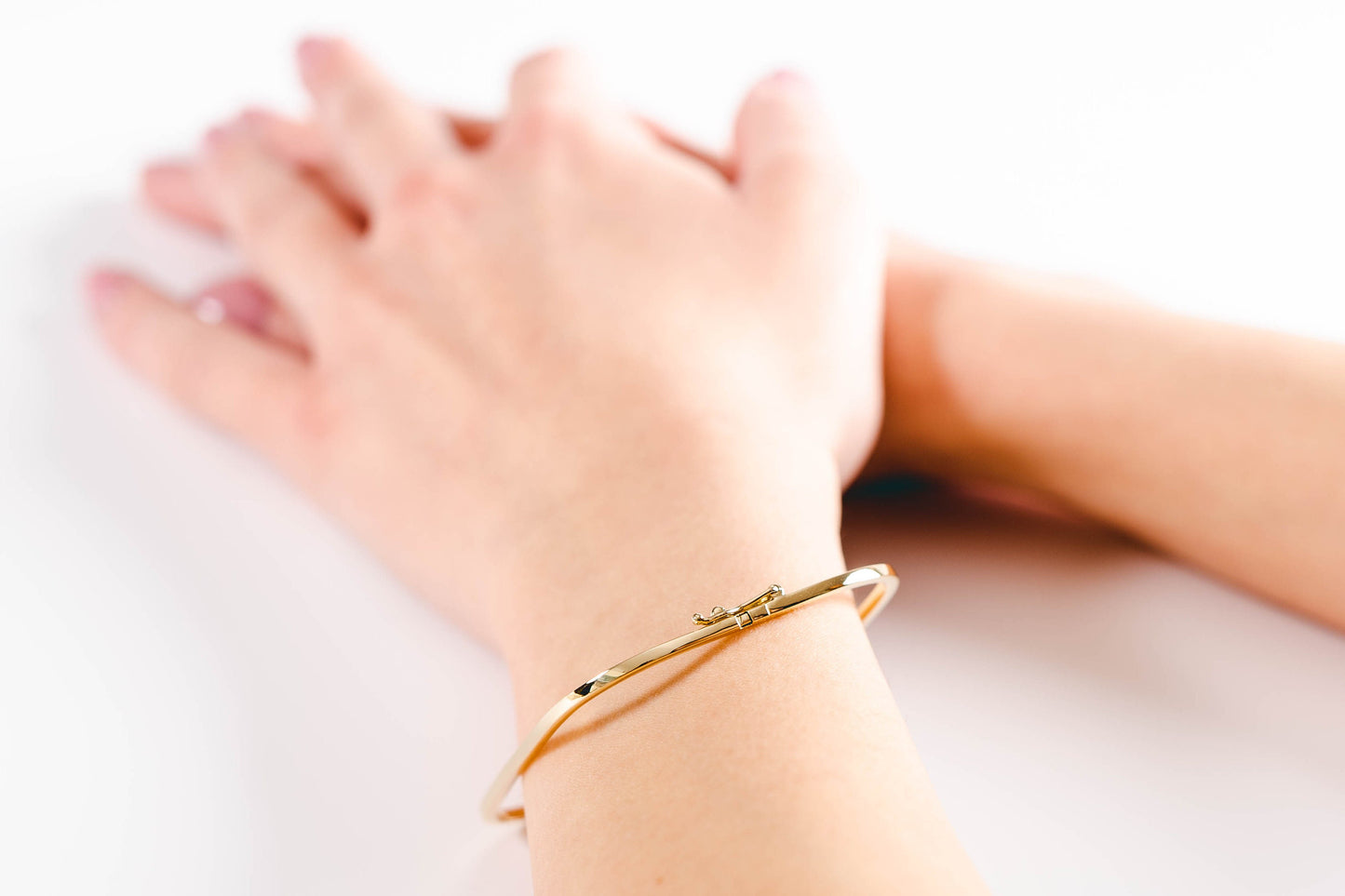 A model wearing a square bangle bracelet crafted in 14k gold for women.