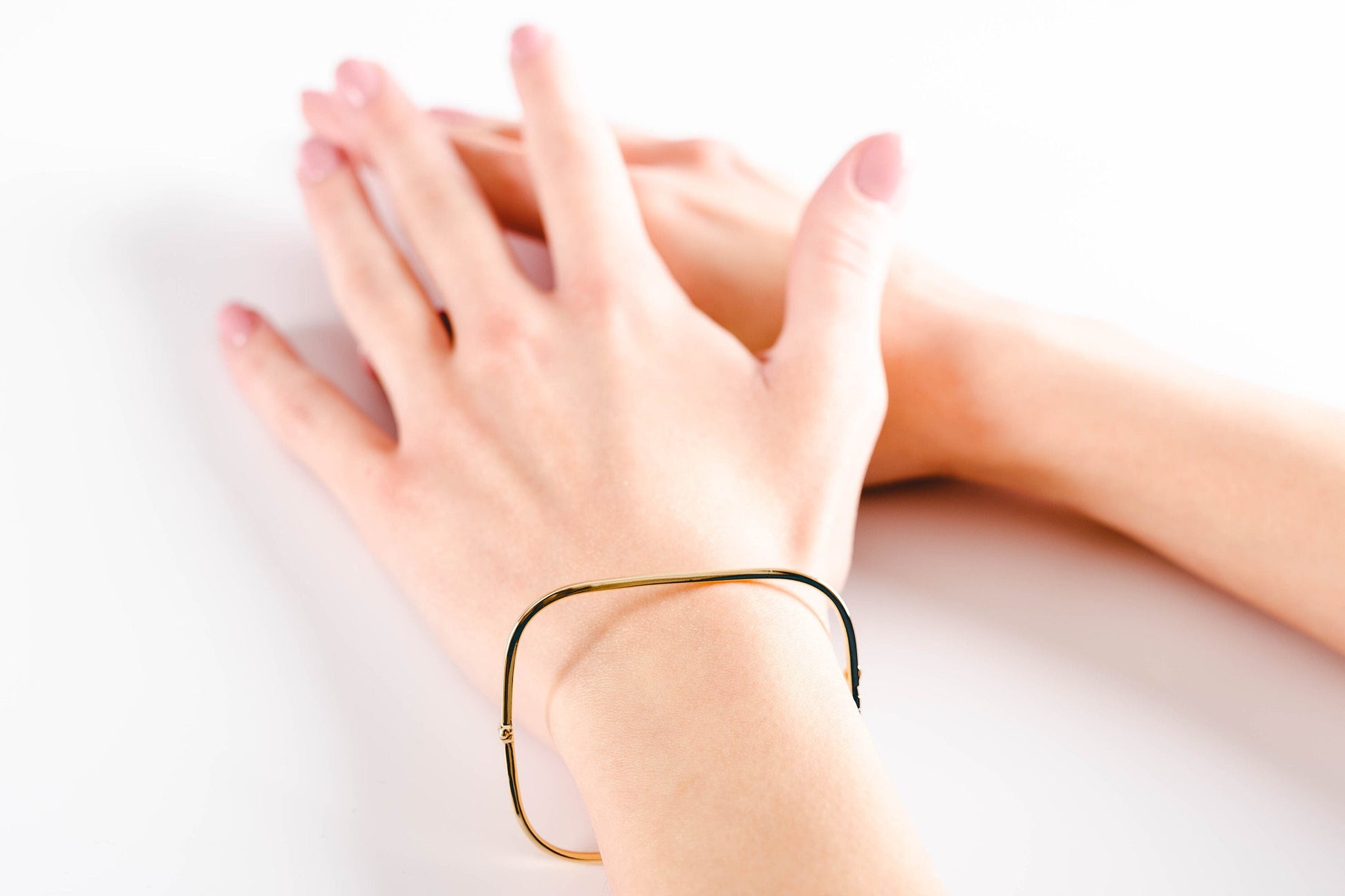 A model wearing a square bangle bracelet crafted in 14k gold for women.