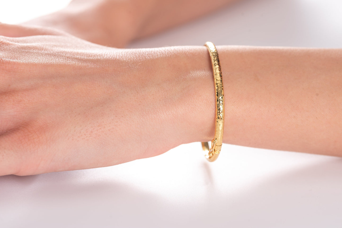 A 4.20mm hammered bangle bracelet in 14k gold, designed for women to adorn their wrist.