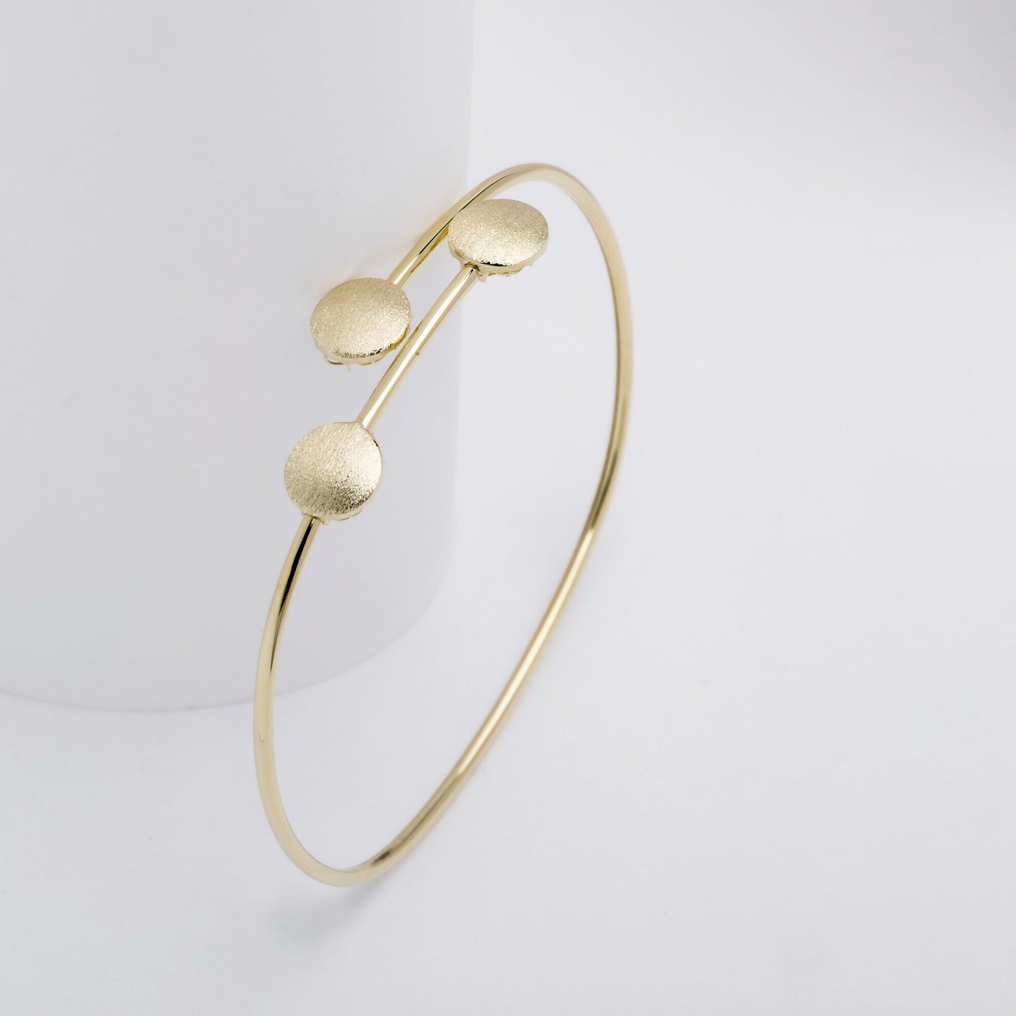 This photo features a minimalist gold open cuff bracelet with three textured round accents on the top.