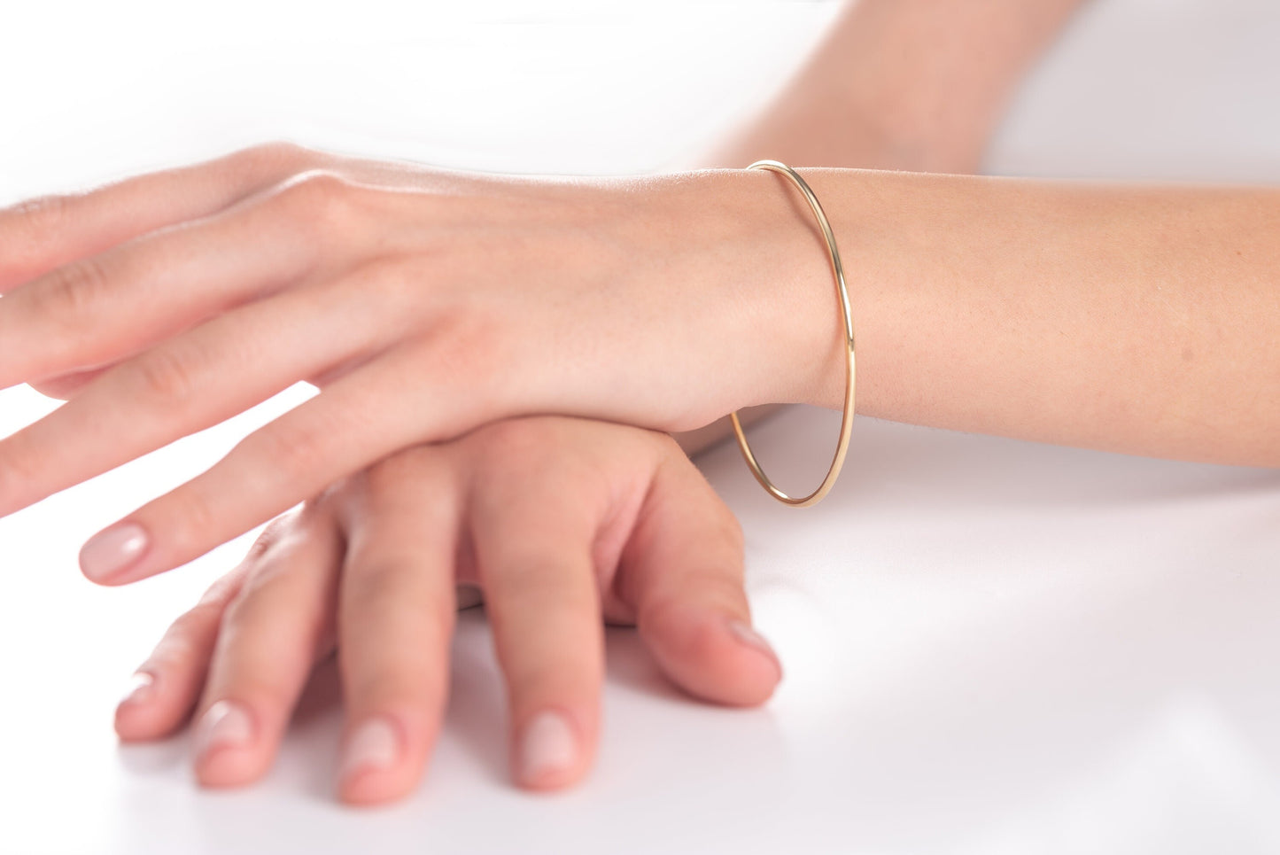 Slip on a 14k Gold Bangle Bracelet for women, showcased by a model.