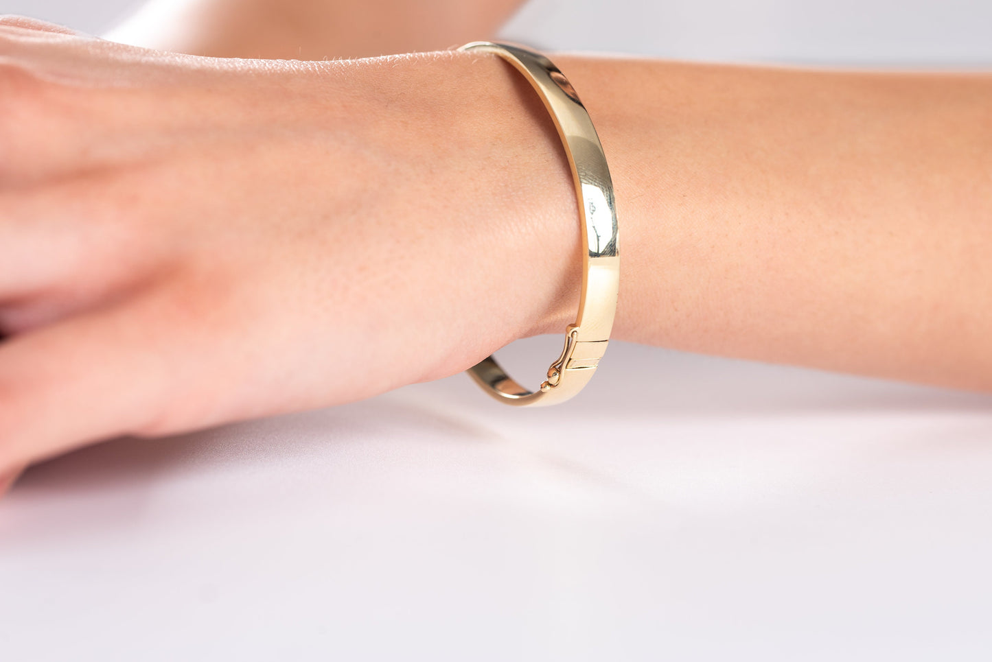 A 6.00mm hinged bangle bracelet crafted in 14k gold for women.