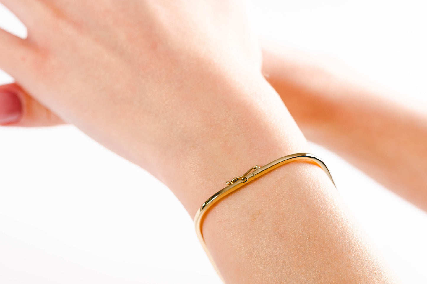 A model wearing a square bangle bracelet crafted in 14k gold for women.