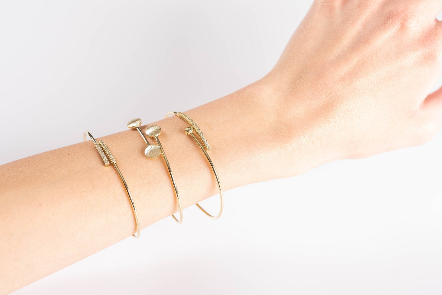 three differnet style thin brangle bracelets worn on a wrist by a model