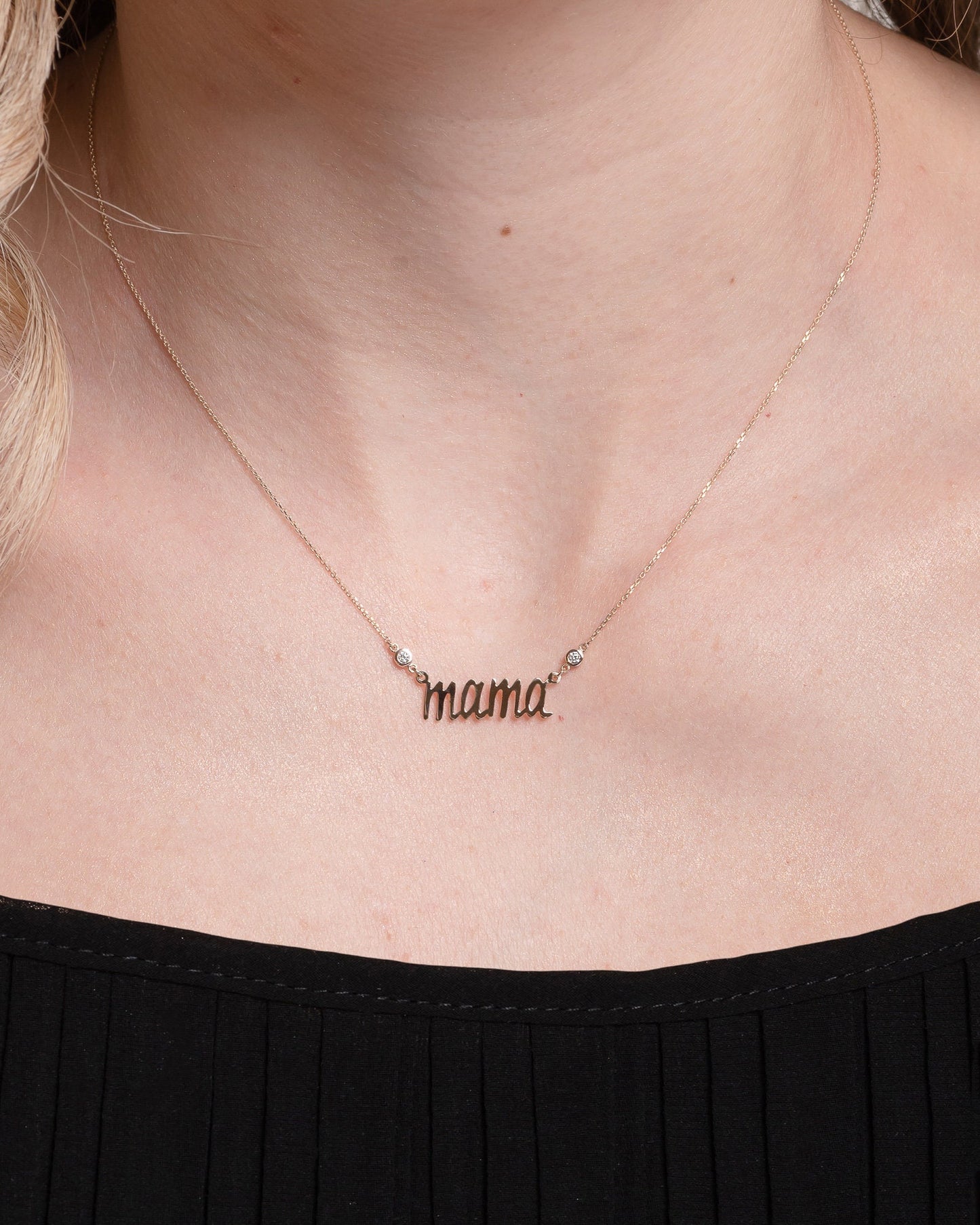 14k gold necklace with the word mama in a cursive script it is adorned with two cubic zirconia stones on each side of the word