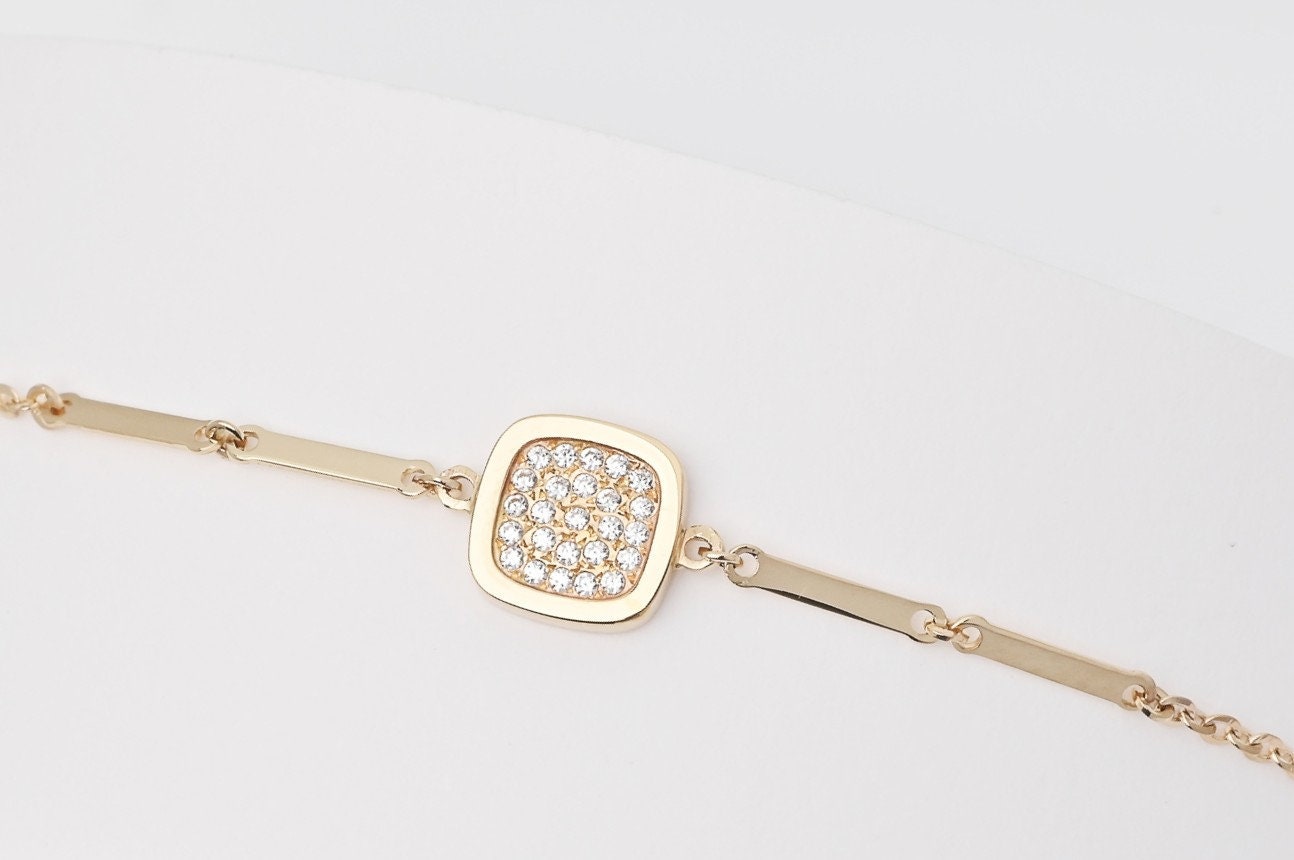 a 14k gold charm bracelet with a square charm paved with white cubic zirconia stones