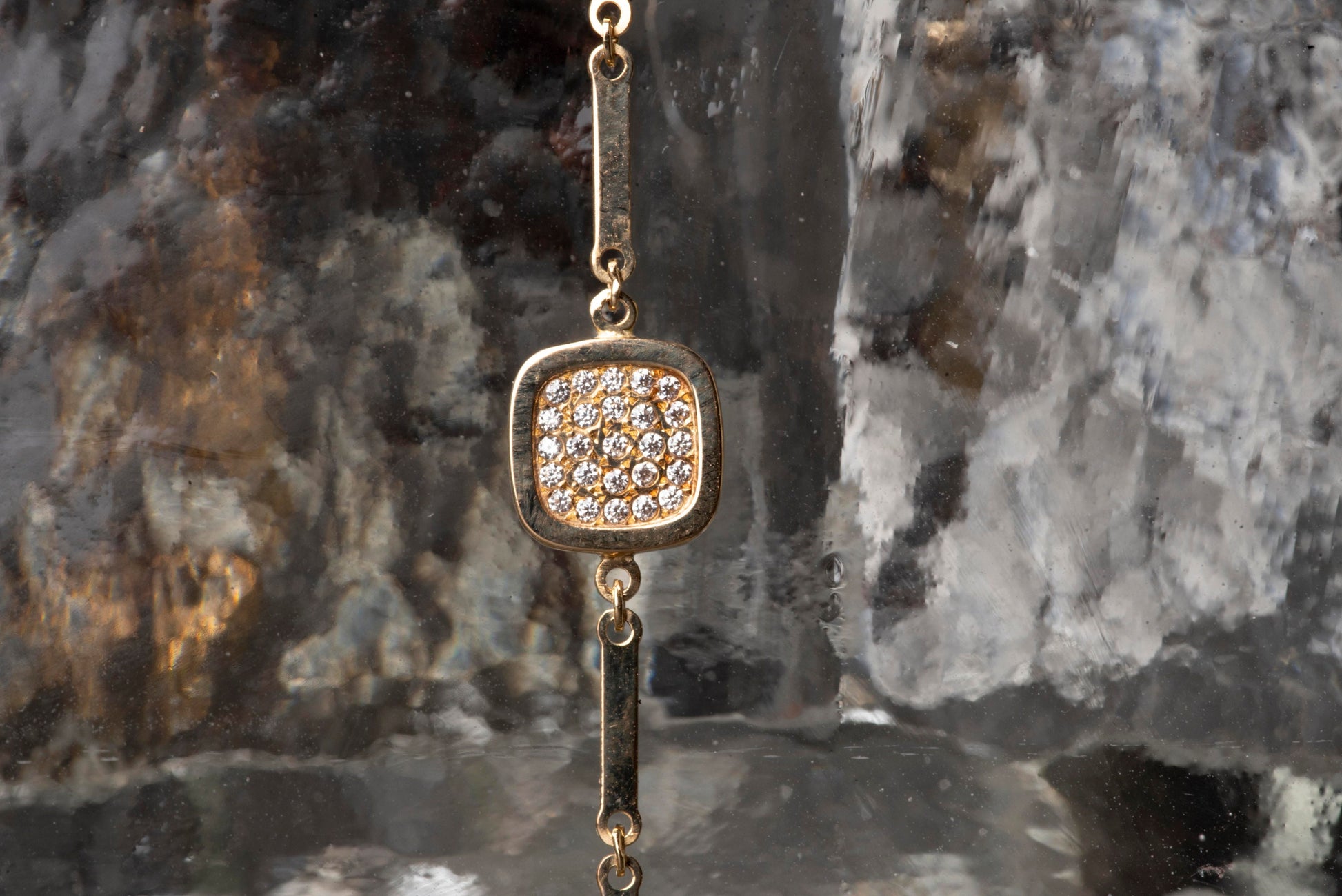 a 14k gold charm bracelet with a square charm paved with white cubic zirconia stones