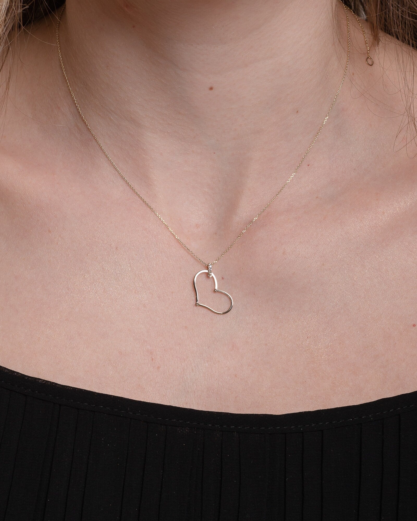 Large Heart Necklace in 14k solid gold with cubic zirconia stones on the loop worn by a model 