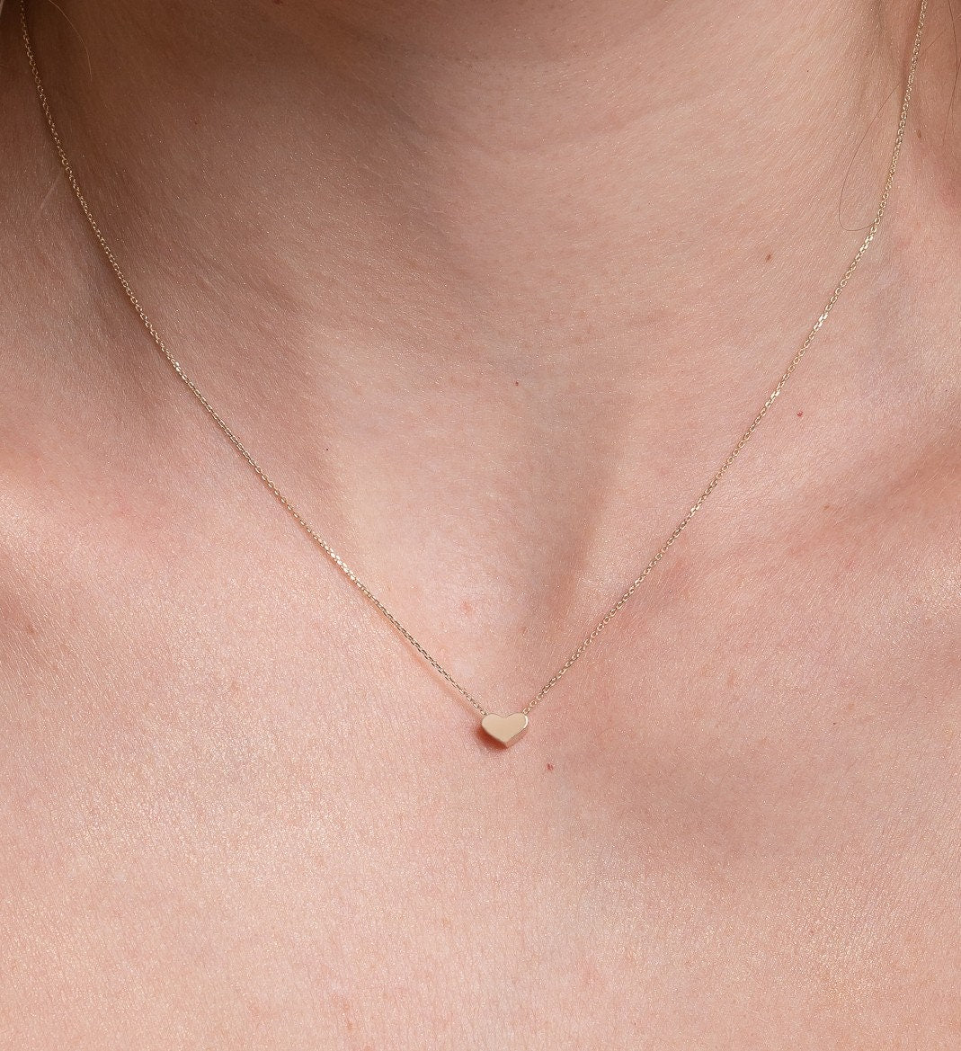 dainty heart necklace in 14k yellow gold worn by a model 