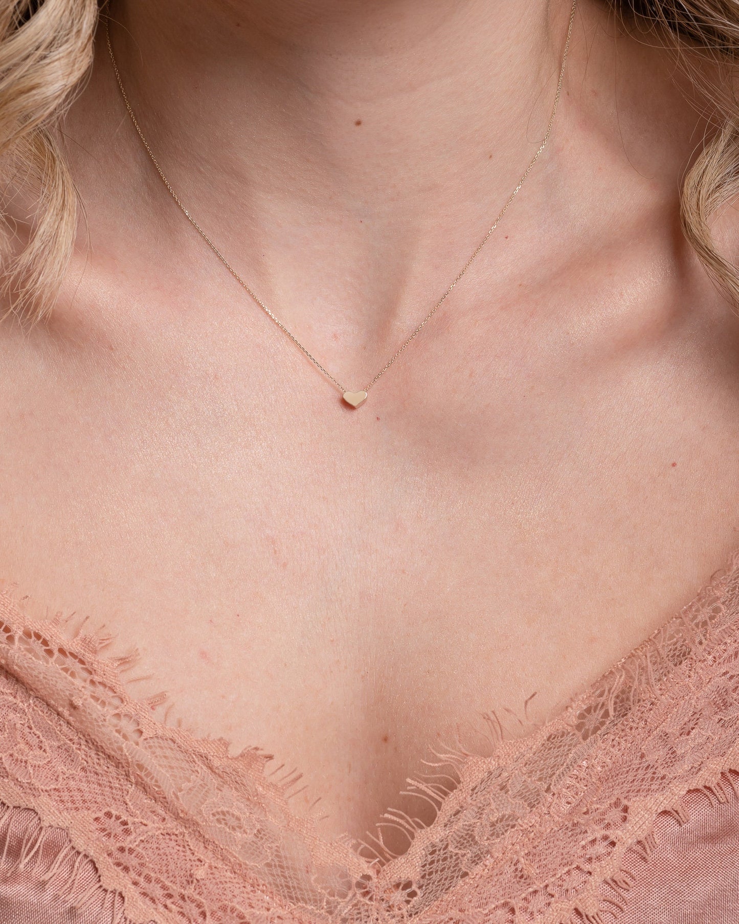 dainty heart necklace in 14k yellow gold worn by a model 