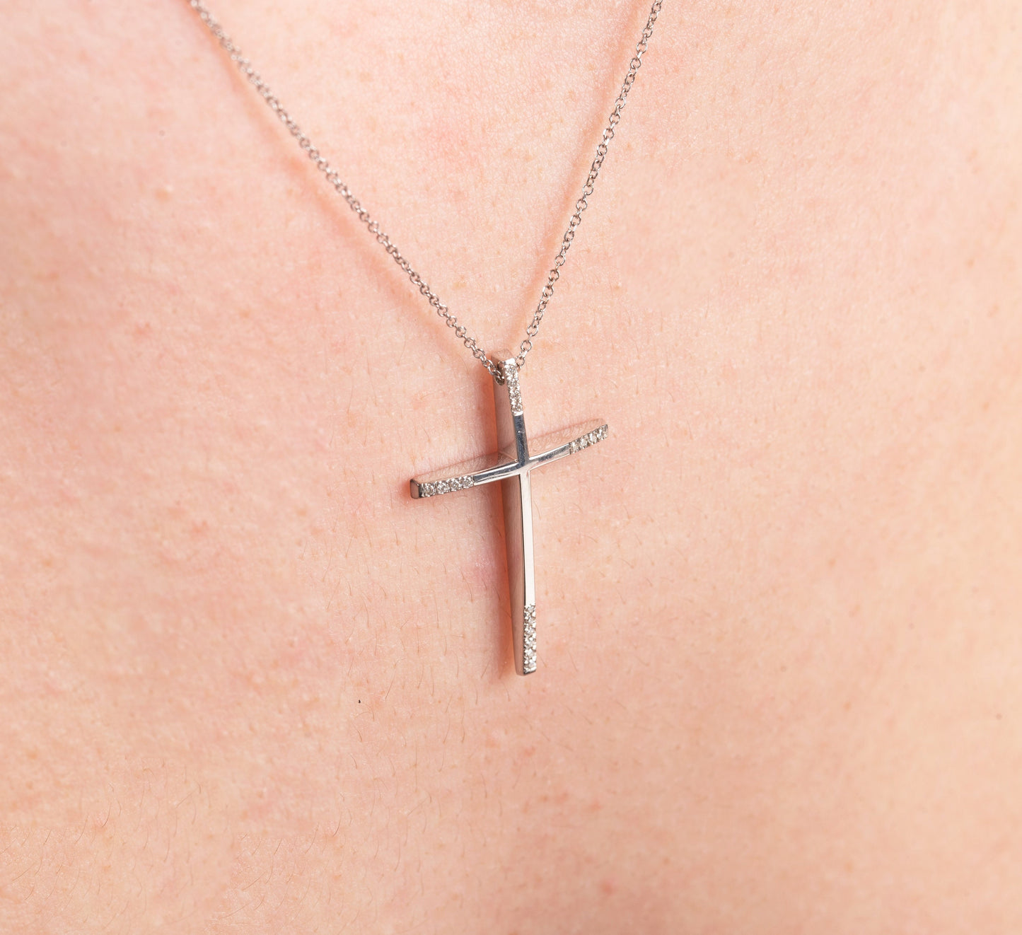 slim diamond cross necklace in 18k white gold for women worn by a model 