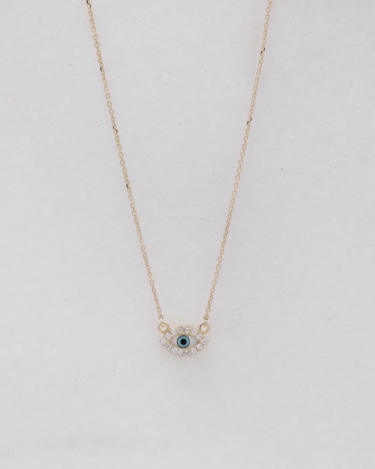 An oval-shaped evil eye necklace featuring mother of pearl and cubic zirconia stones, set in 14k gold for women.