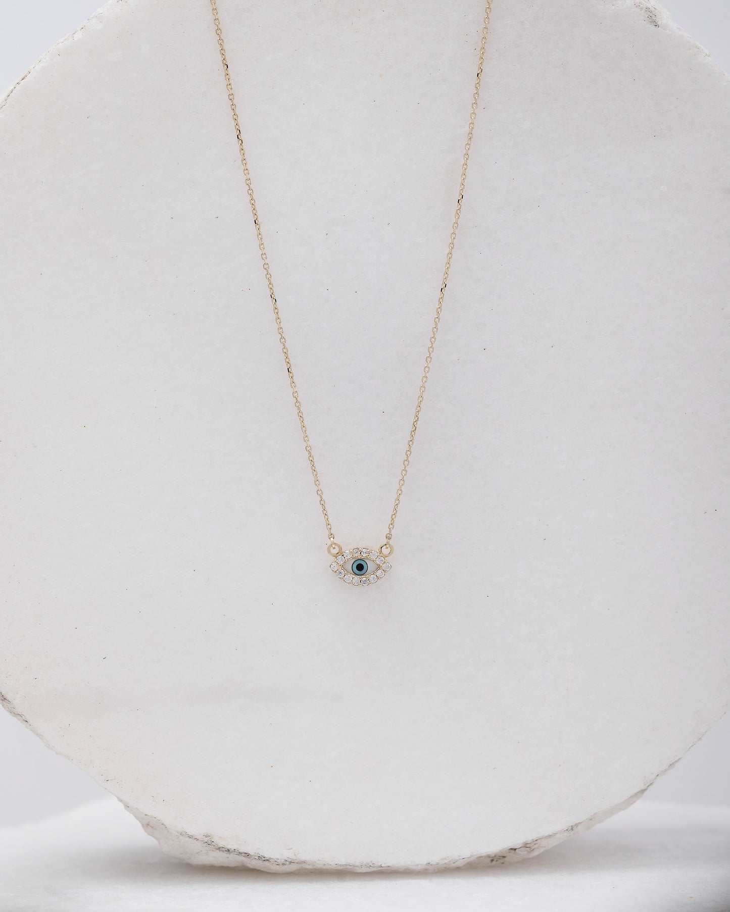 An oval-shaped evil eye necklace featuring mother of pearl and cubic zirconia stones, set in 14k gold for women.