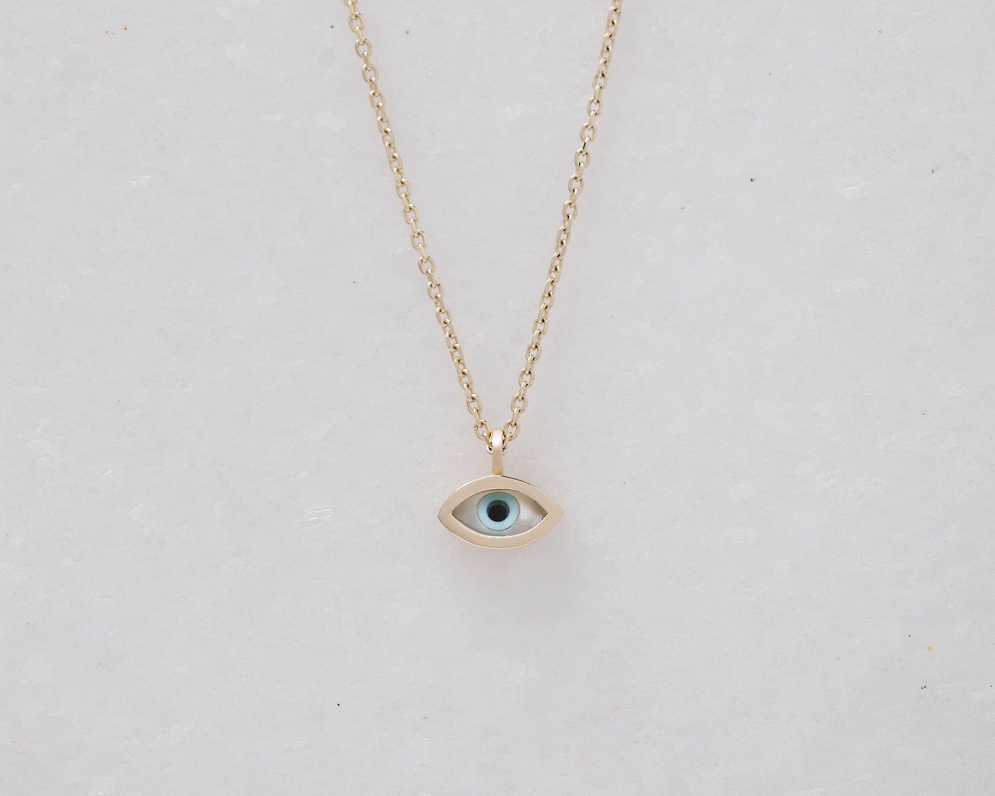 Tiny mother-of-pearl evil eye necklace in 14k gold for women.