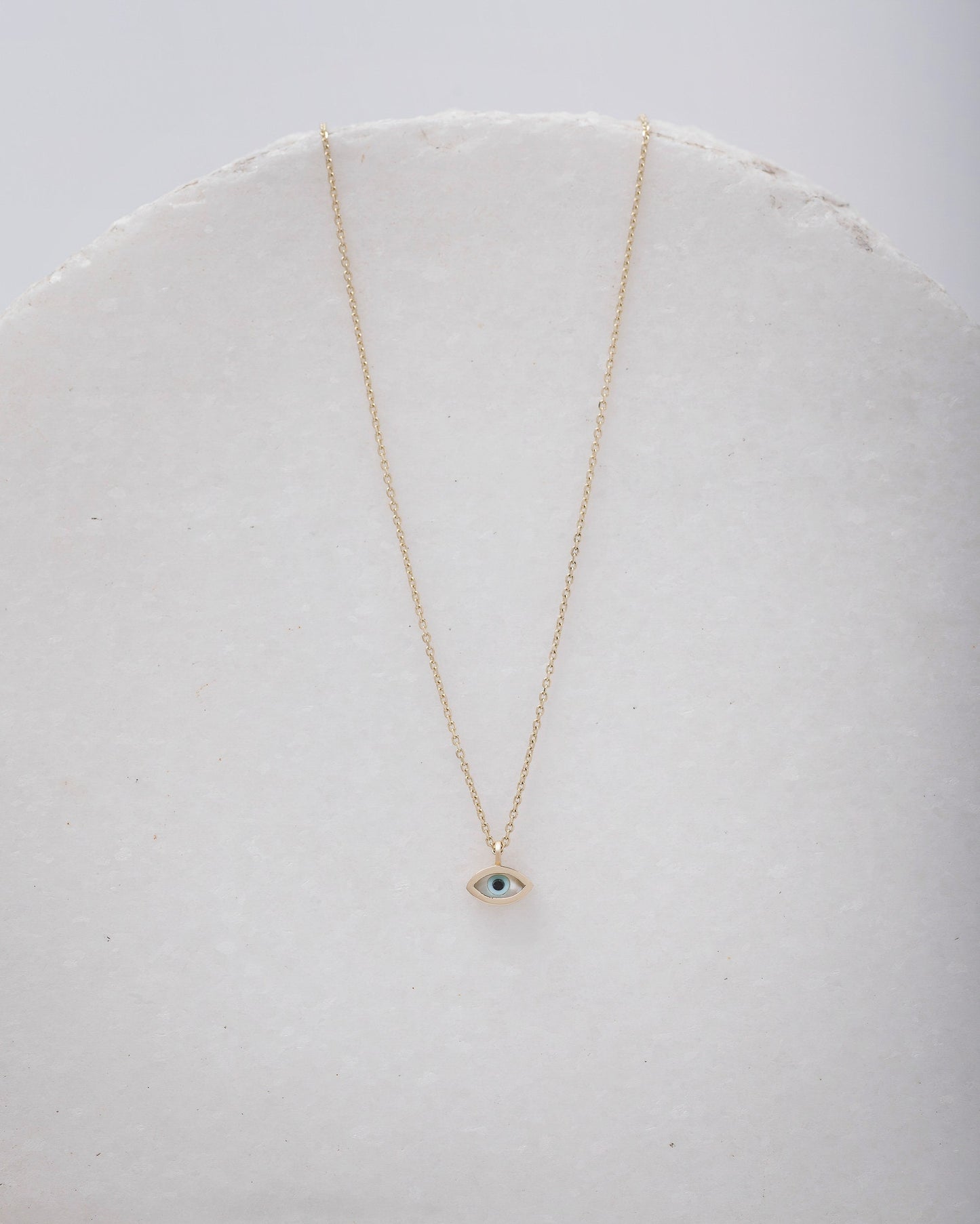 Tiny mother-of-pearl evil eye necklace in 14k gold for women.