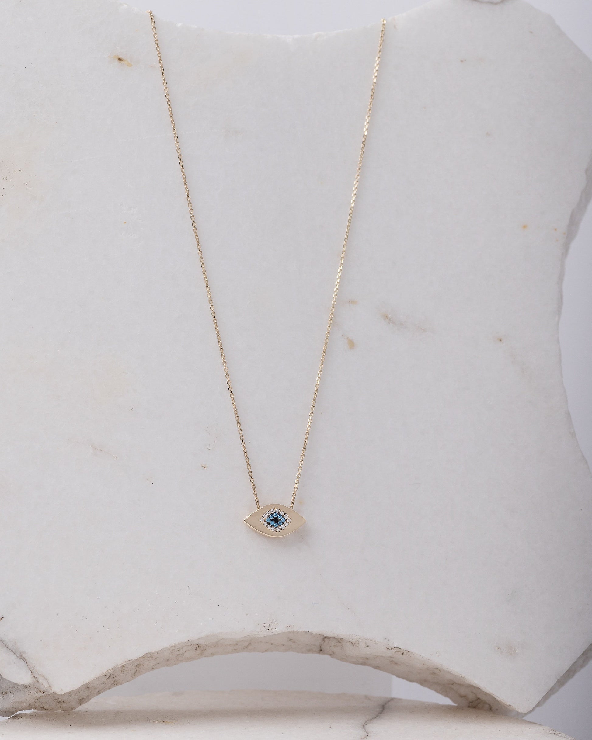 An oval-shaped evil eye necklace crafted in 14k gold and encrusted with cubic zirconia stones.