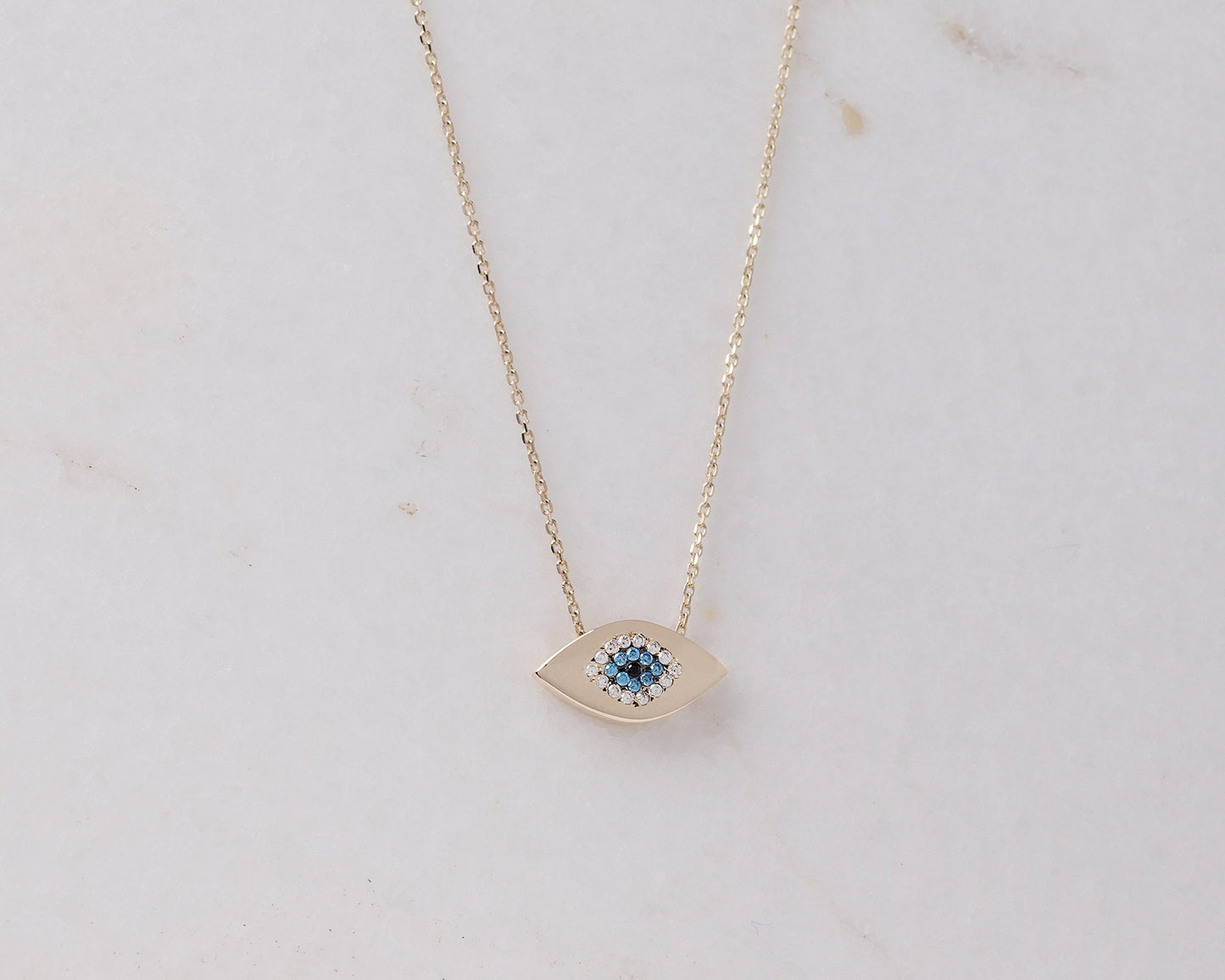 An oval-shaped evil eye necklace crafted in 14k gold and encrusted with cubic zirconia stones.