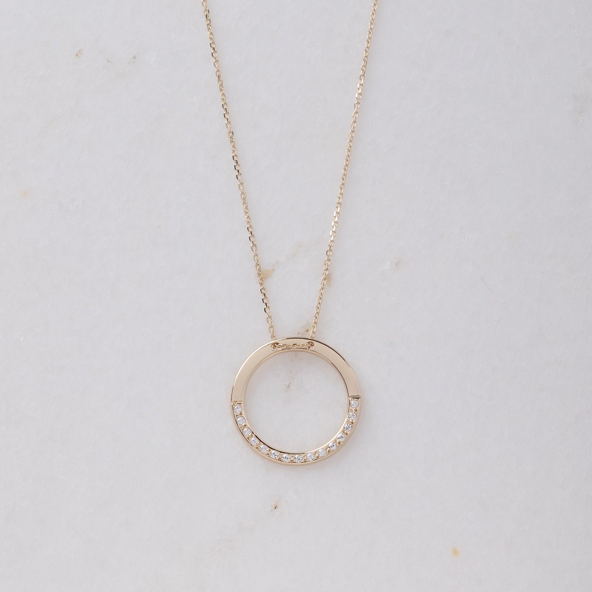 circle karma necklce in 14k gold half of the necklace is paved with cubic zirconia stones